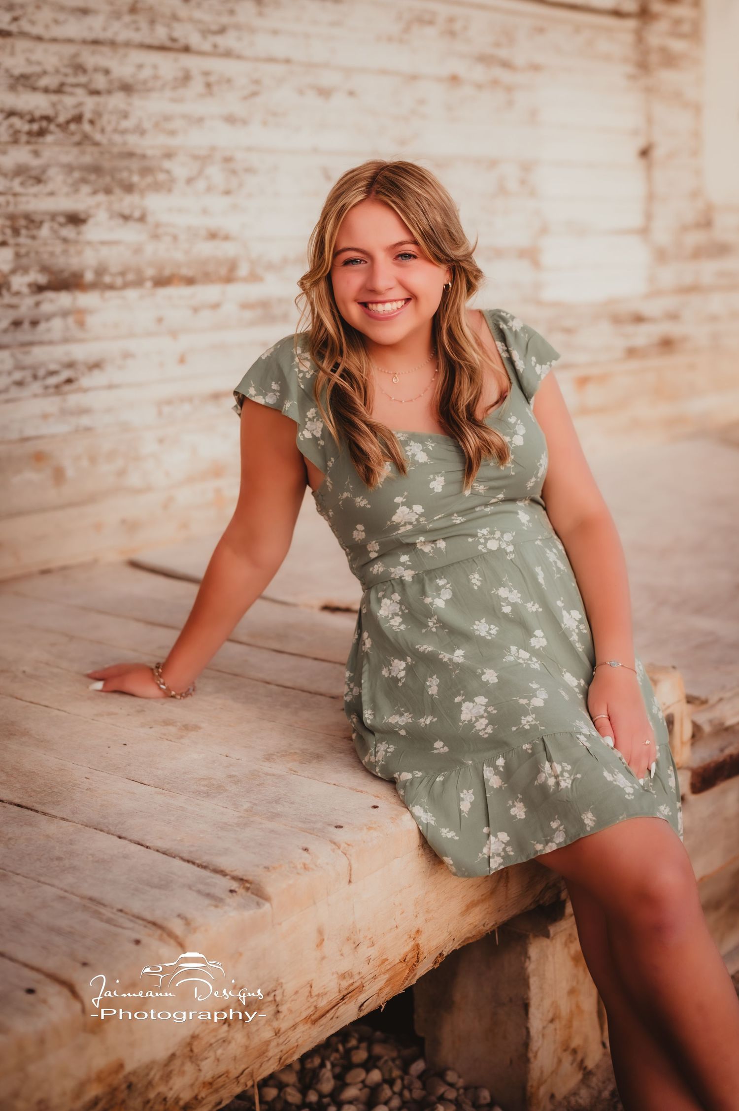 A casual summer portrait on wooden steps wearing a sage green floral dress.