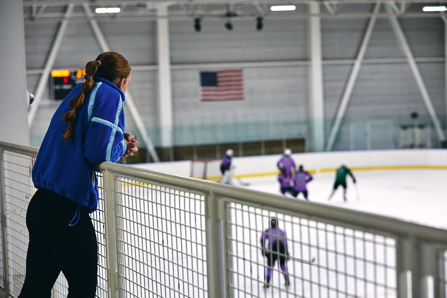 Fan watching a beer league hockey game from the stands above the ice