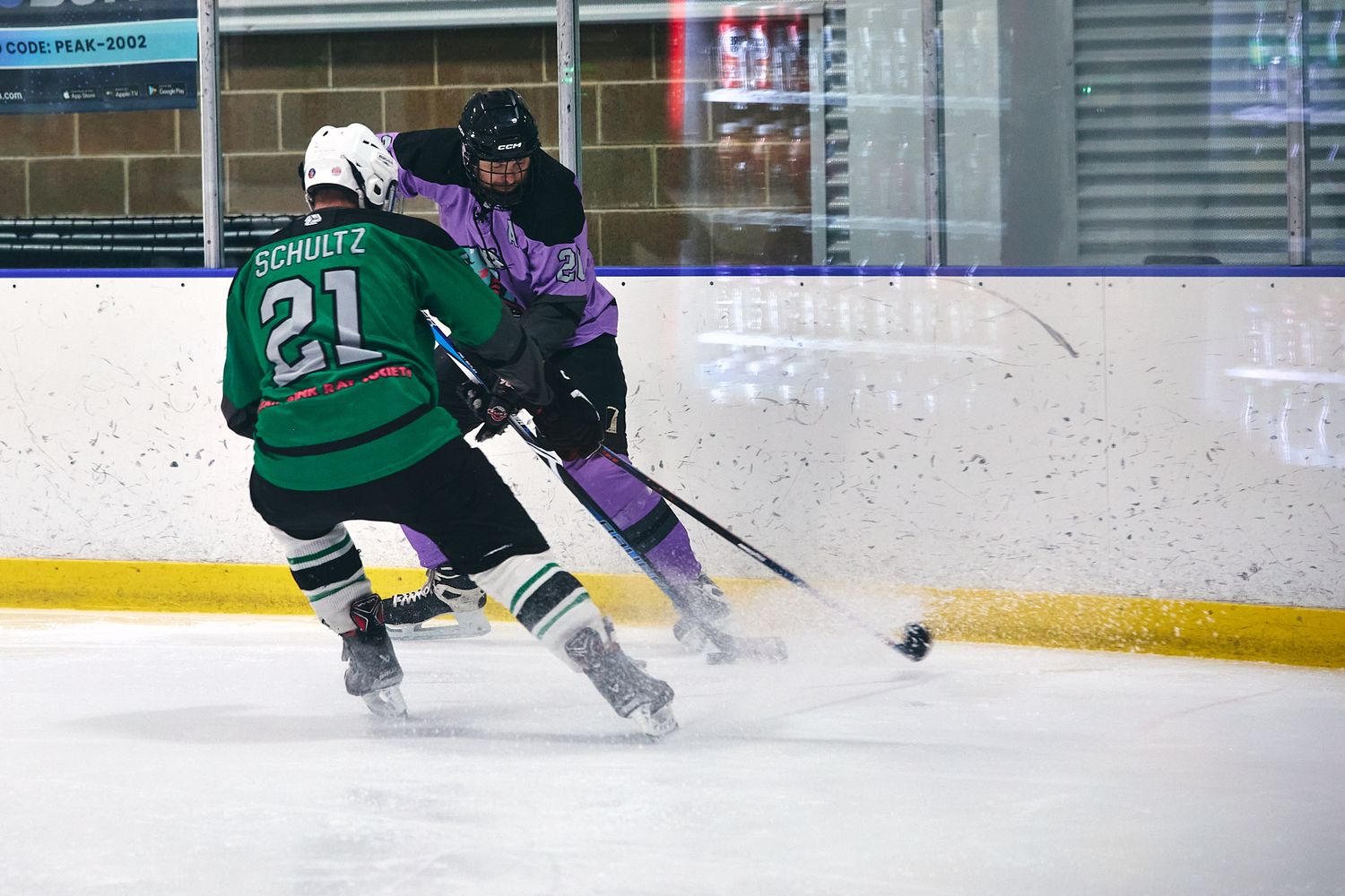 Adult hockey players battling for the puck along the boards