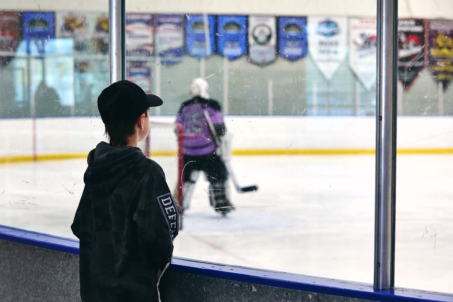 Fan watching a beer league hockey game from behind the glass