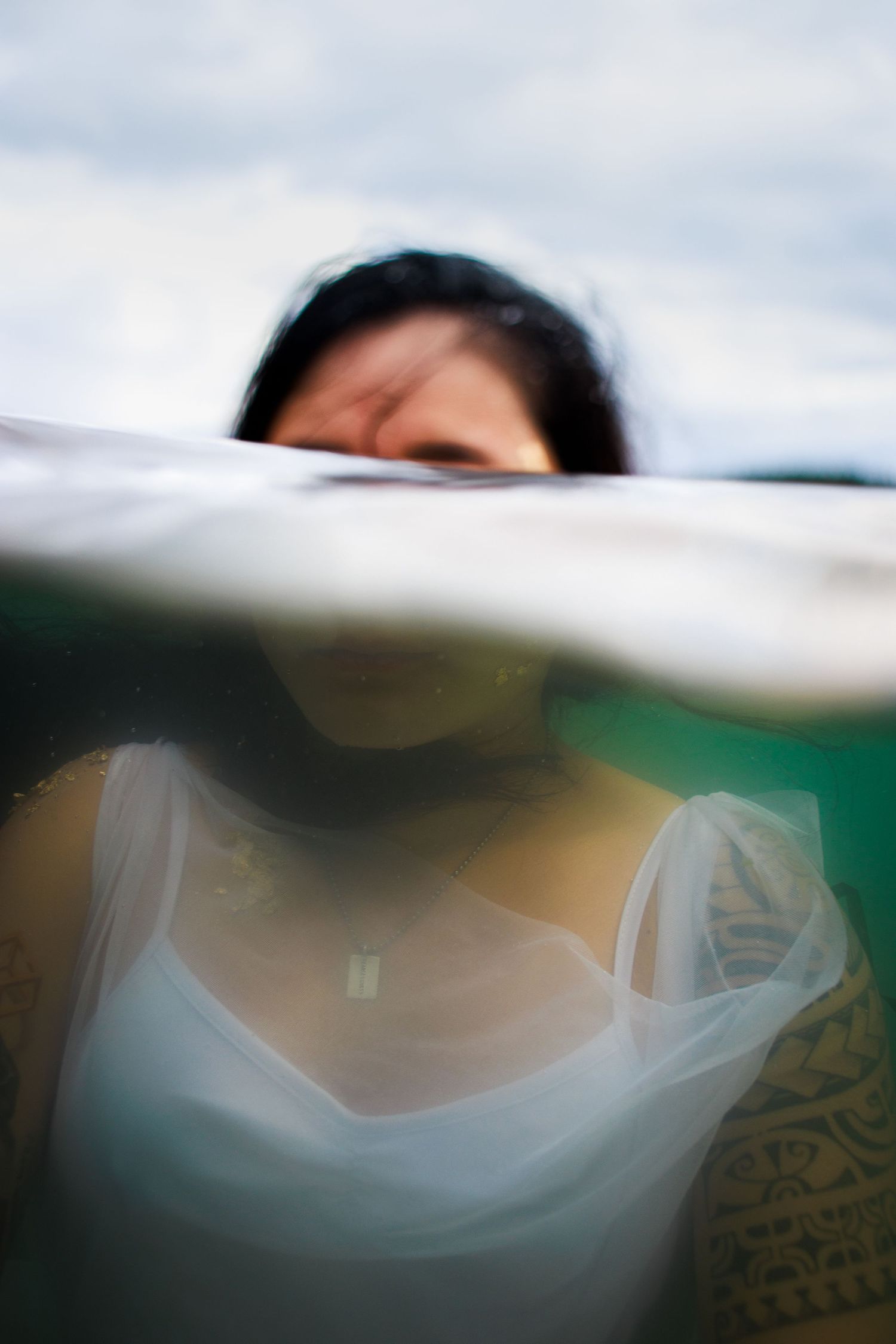 A split shot of a woman in a white dress floating in the ocean.