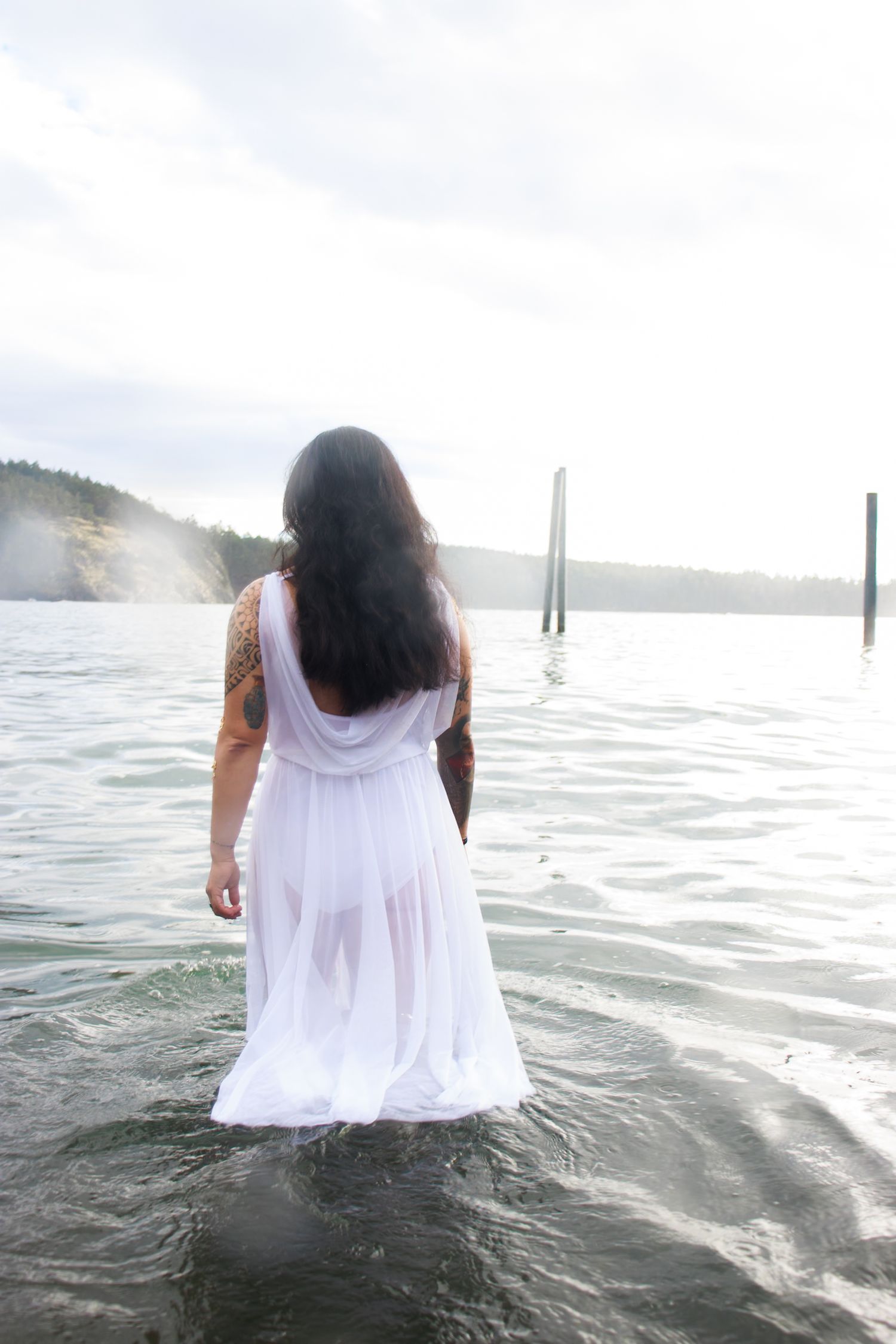 A photo of a woman in a white dress walking into the ocean.