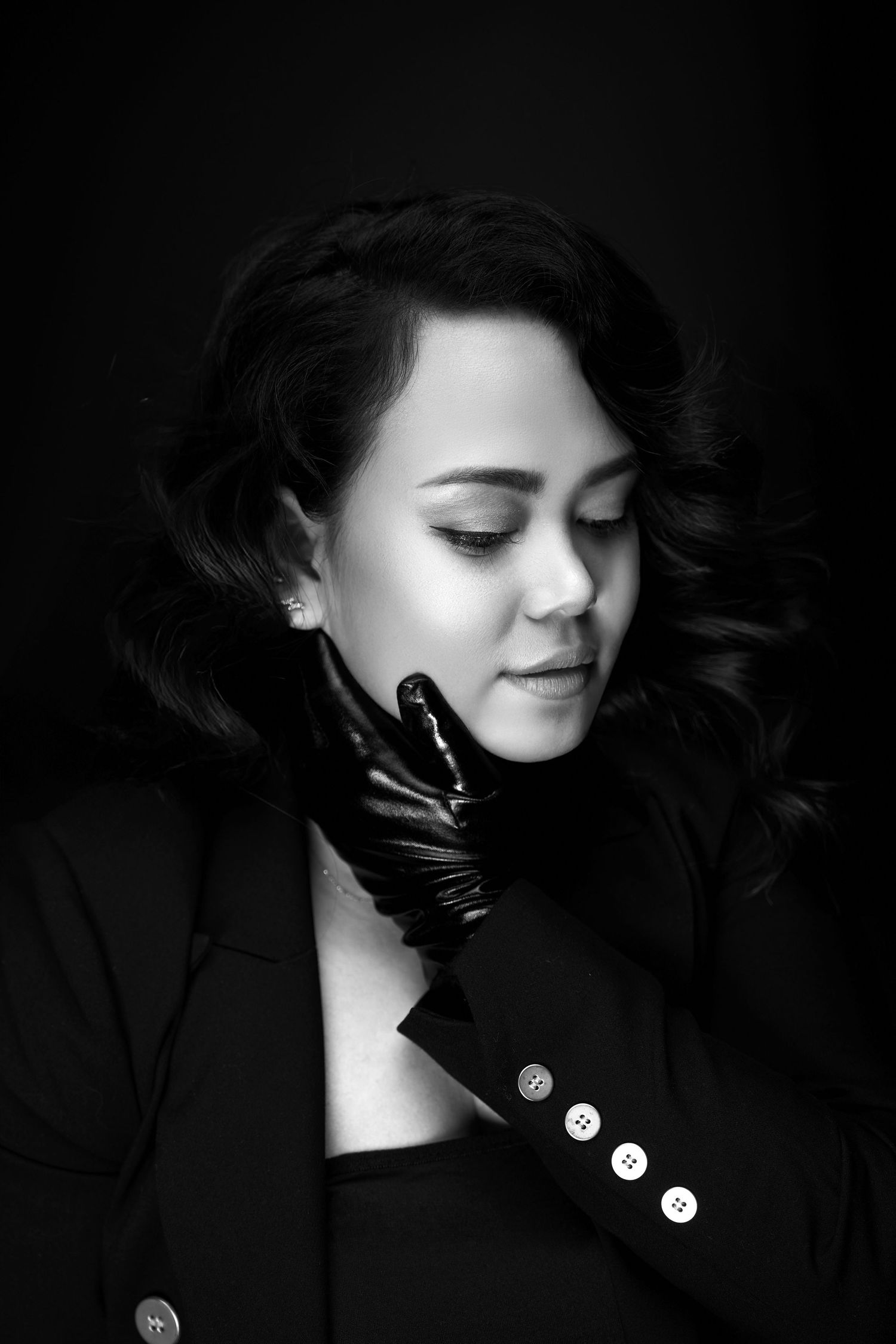 Black and white portrait featuring dramatic shadows and coat with decorative buttons.