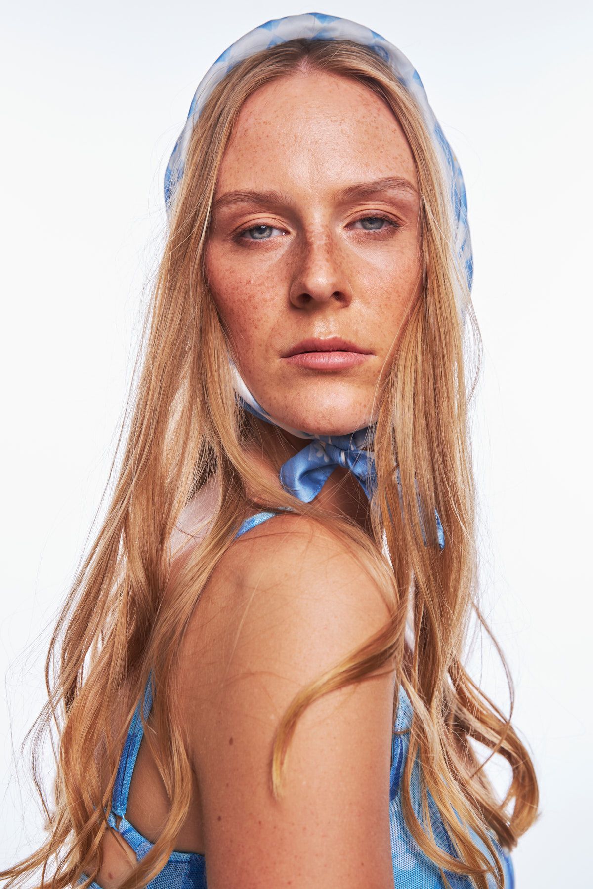 A fashion model with blonde hair poses in a blue swimsuit against a white background Sydney by Studio TingTing.