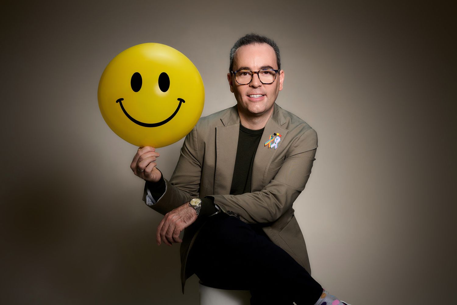 Personal branding portrait of mental health coach holding smiley face balloon in sydney studio.