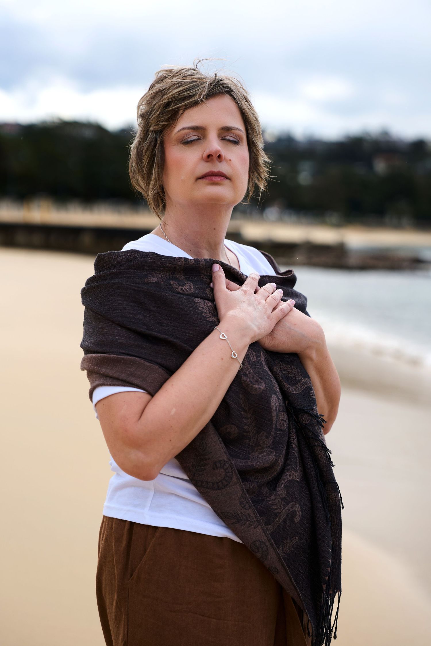 A female founder in casual attire poses with a black scarf against a beach backdrop in balmoral sydney by Studio TingTing.