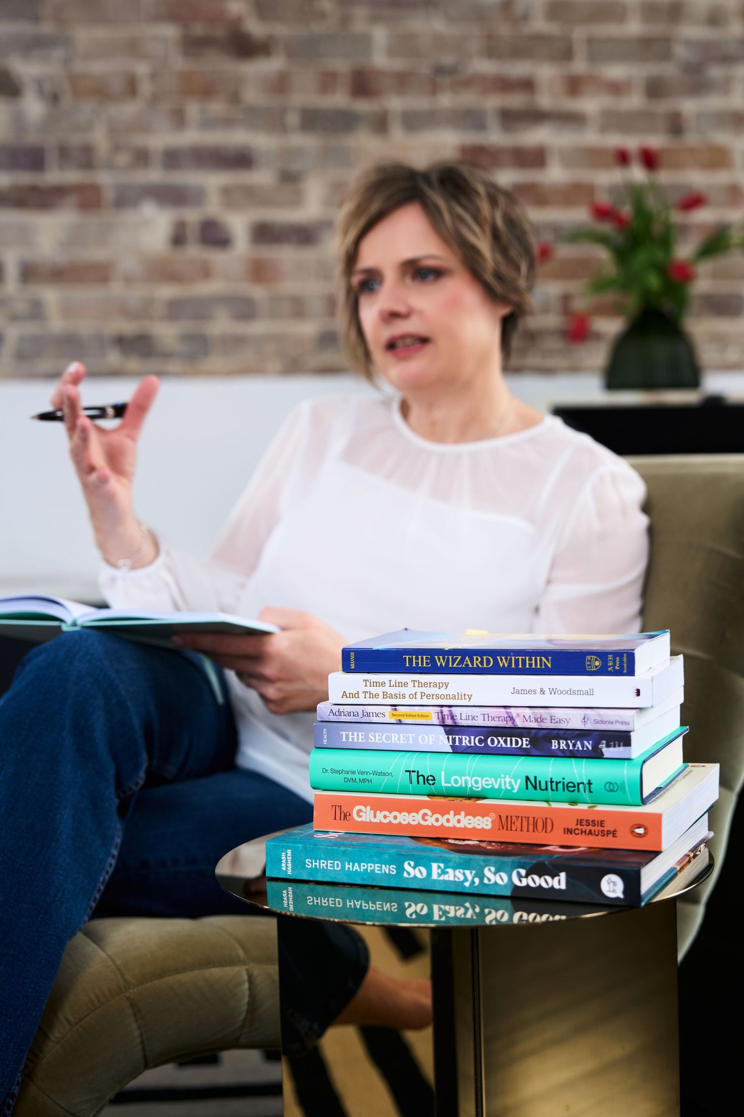 A nutritionist shot candidly with a stack of colorful wellness books on a couch by Studio TingTing in Sydney.
