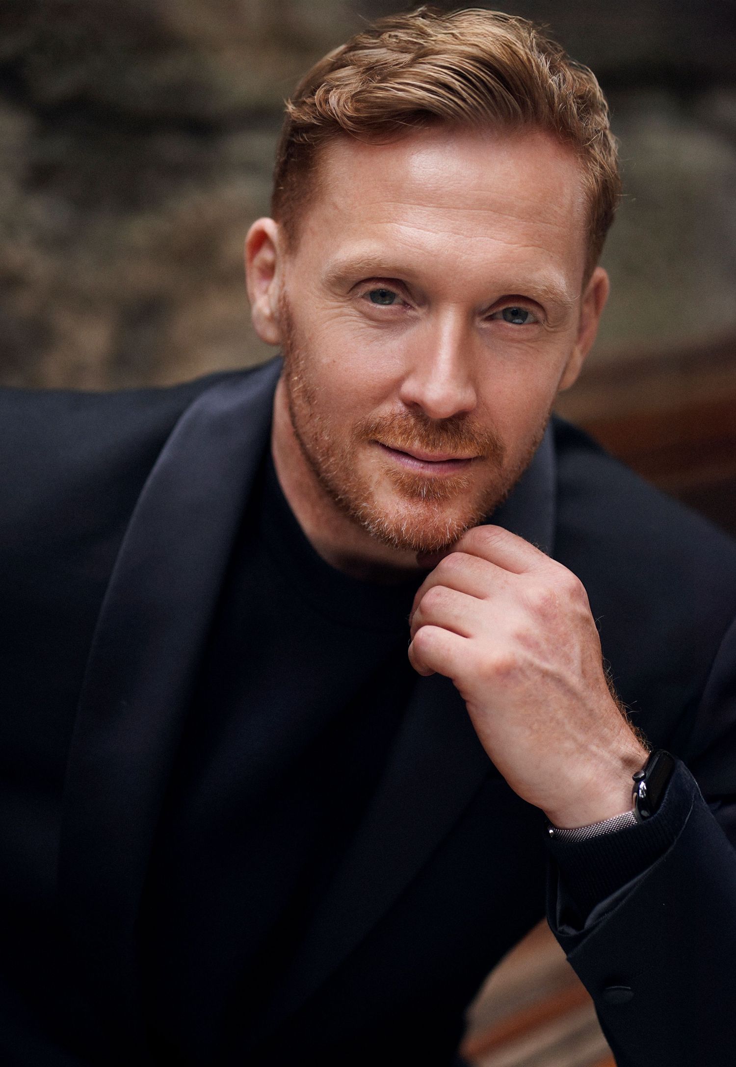 Professional headshot portrait of someone wearing a black suit jacket against a dark background. Studio TingTing.