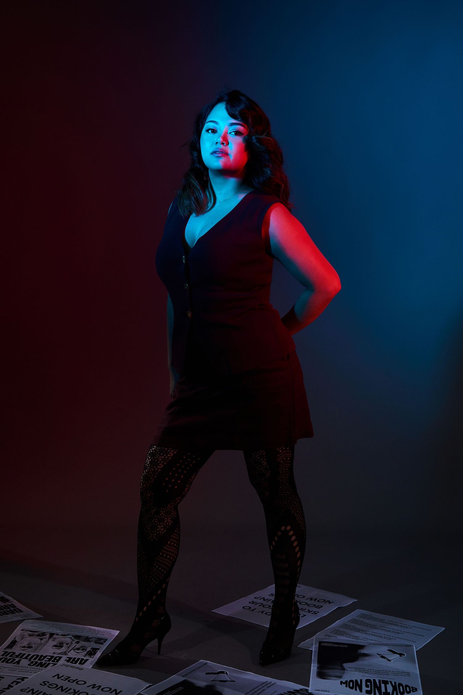 Artistic photo series with a female founder posing on scattered papers under dramatic neon lighting by Studio TingTing.