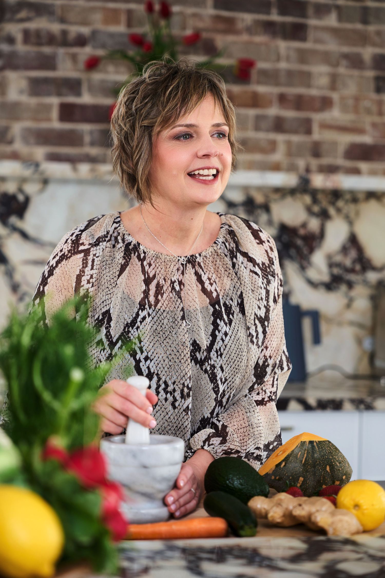 A nutritionist posing at a kitchen counter with fresh produce posing for candid lifestyle branding photos by Studio TingTing in Sydney.