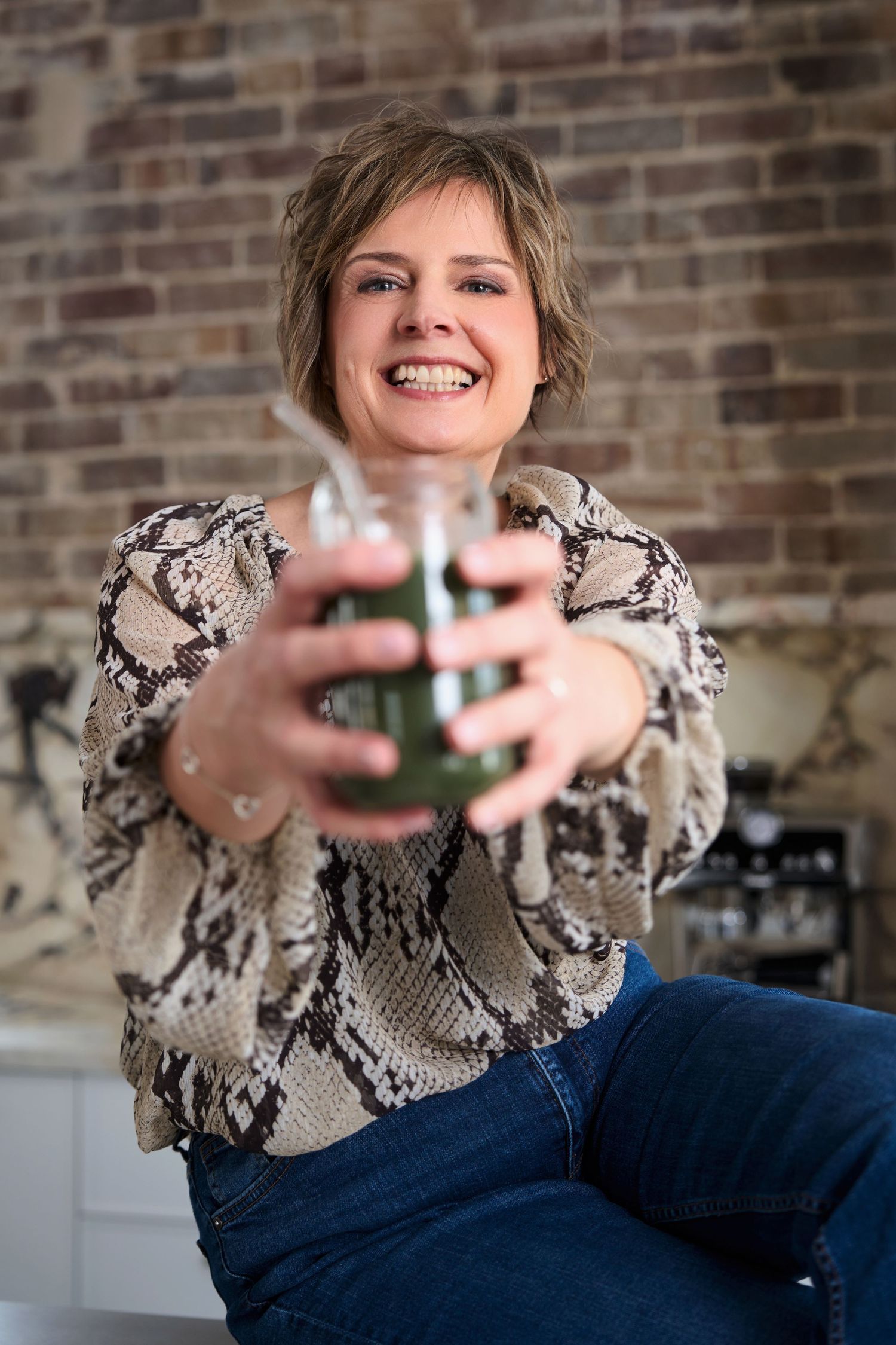 A lifestyle business photo showing a nutritionist holding up a smoothie in a kitchen. Shot by Studio TingTing in Crows Nest.