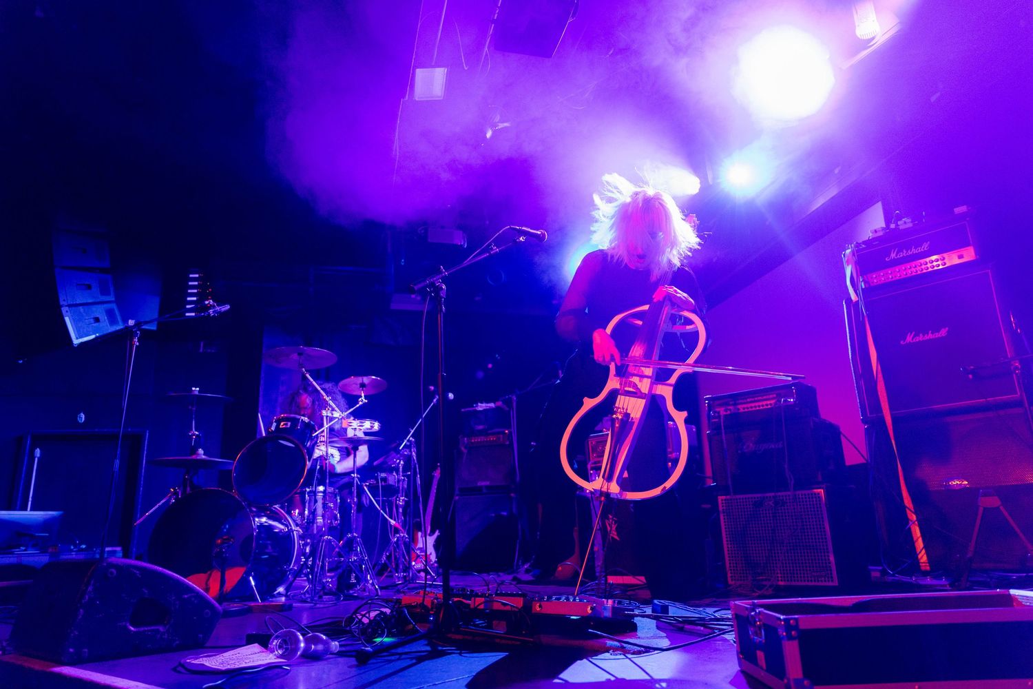 Wide angle view of music stage setup with dramatic purple lighting and instruments.