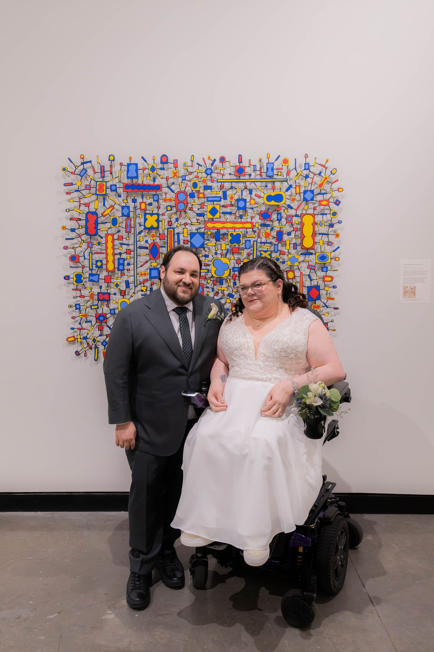 Wedding couple posing in front of a vibrant geometric wall art display.