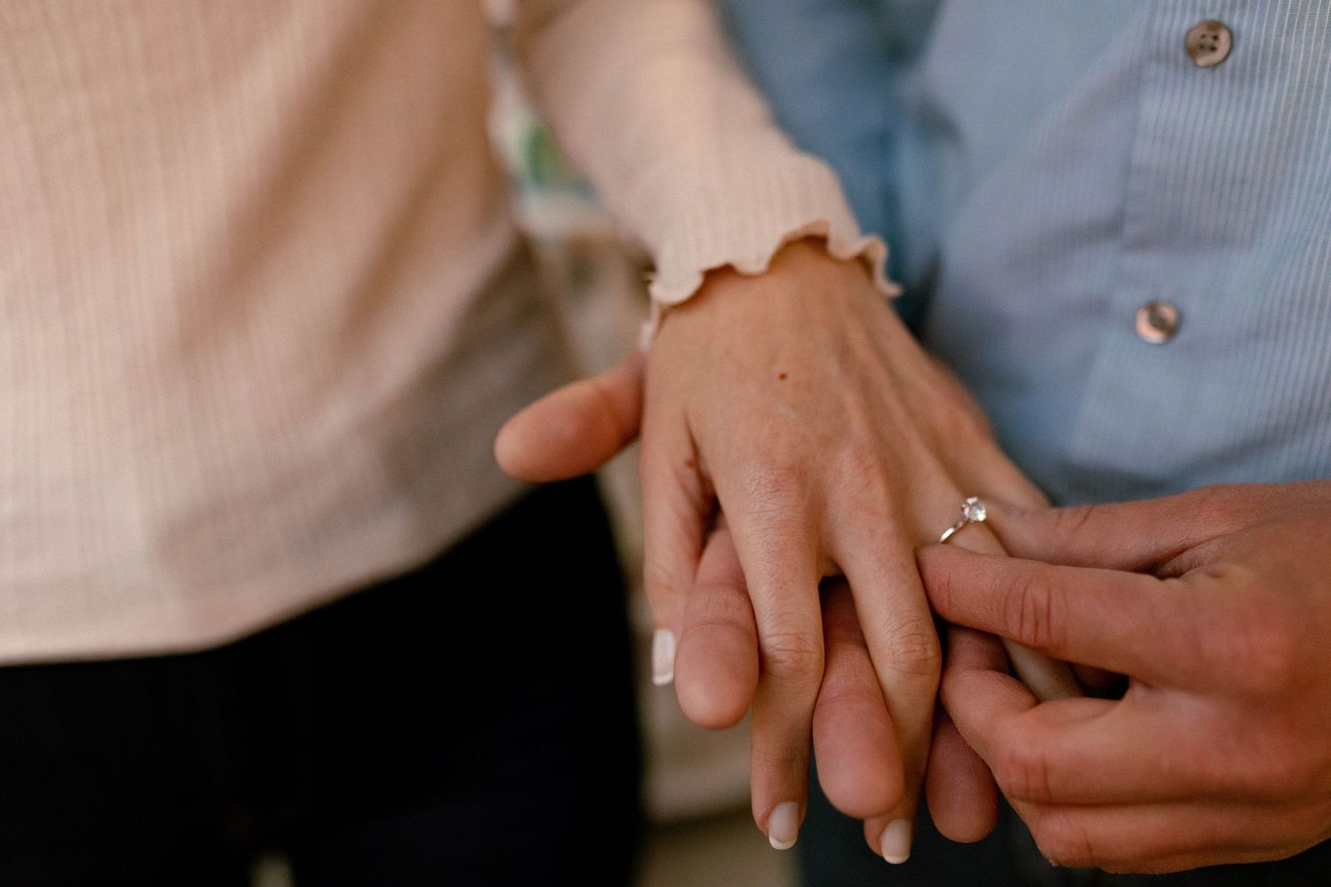 Close-up detail of hands showing engagement or wedding rings.