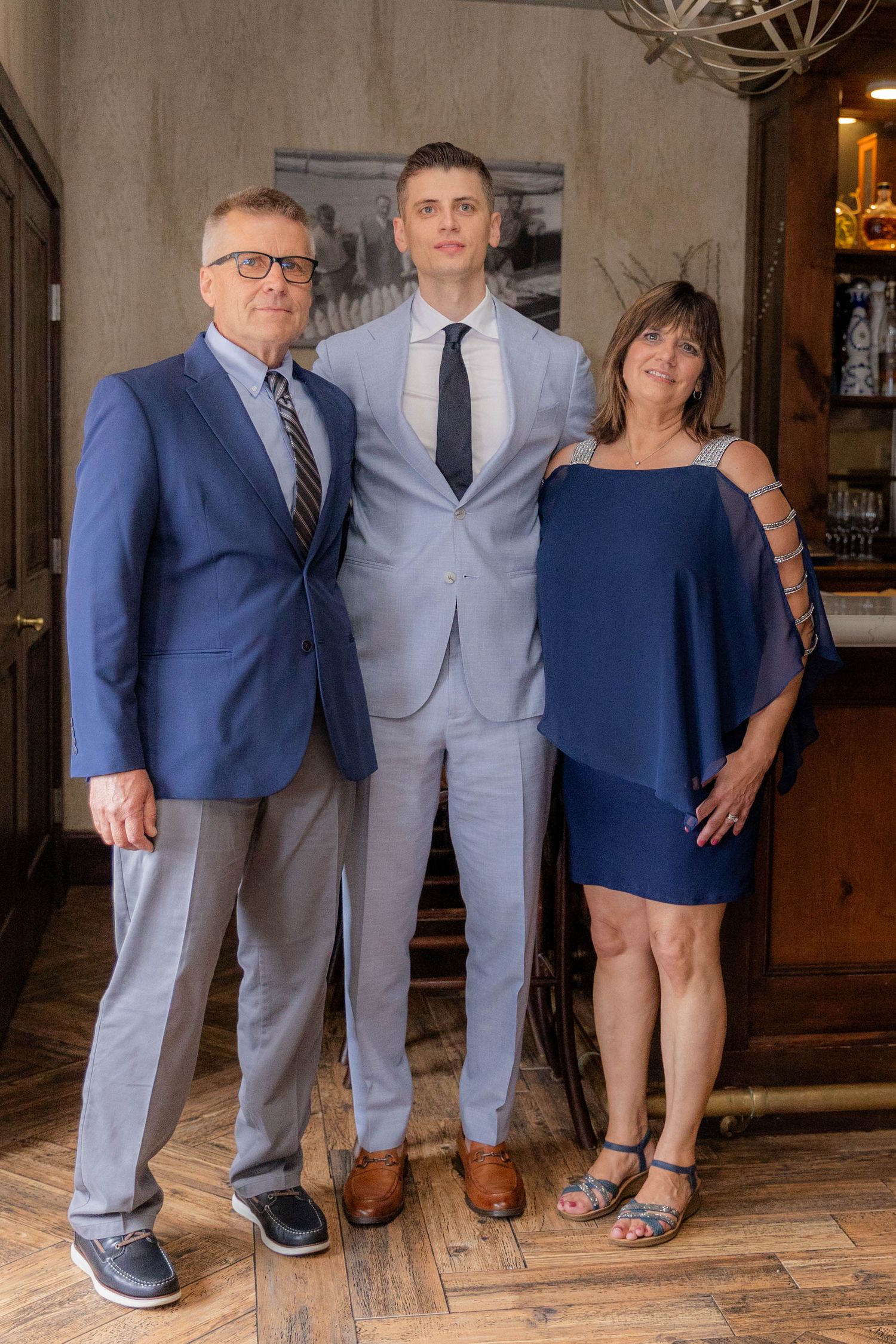 A creative photo series showing only the legs and feet of formally dressed people standing in a line on hardwood flooring.