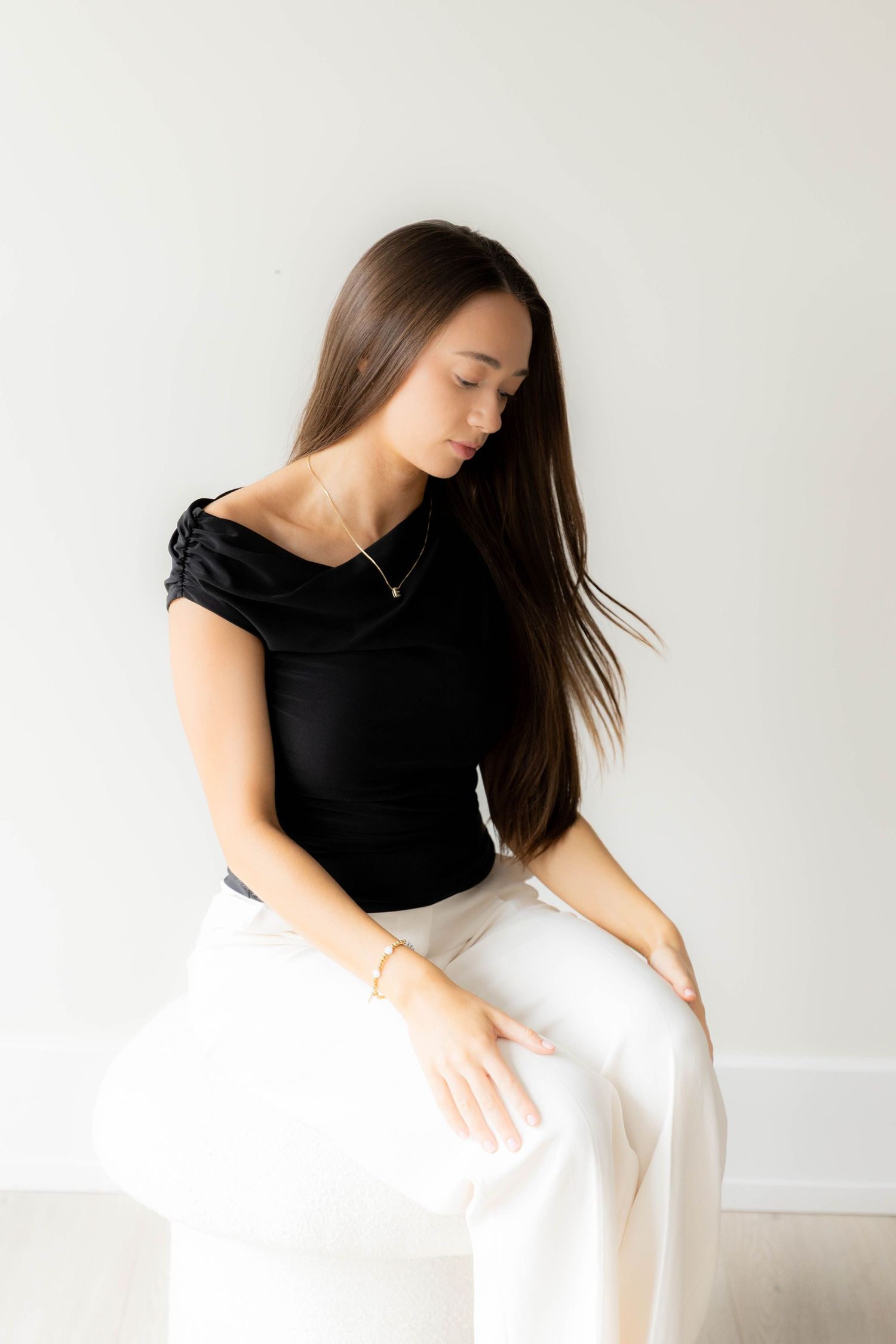 Person in contrasting black and white outfit posing artistically in minimalist setting.