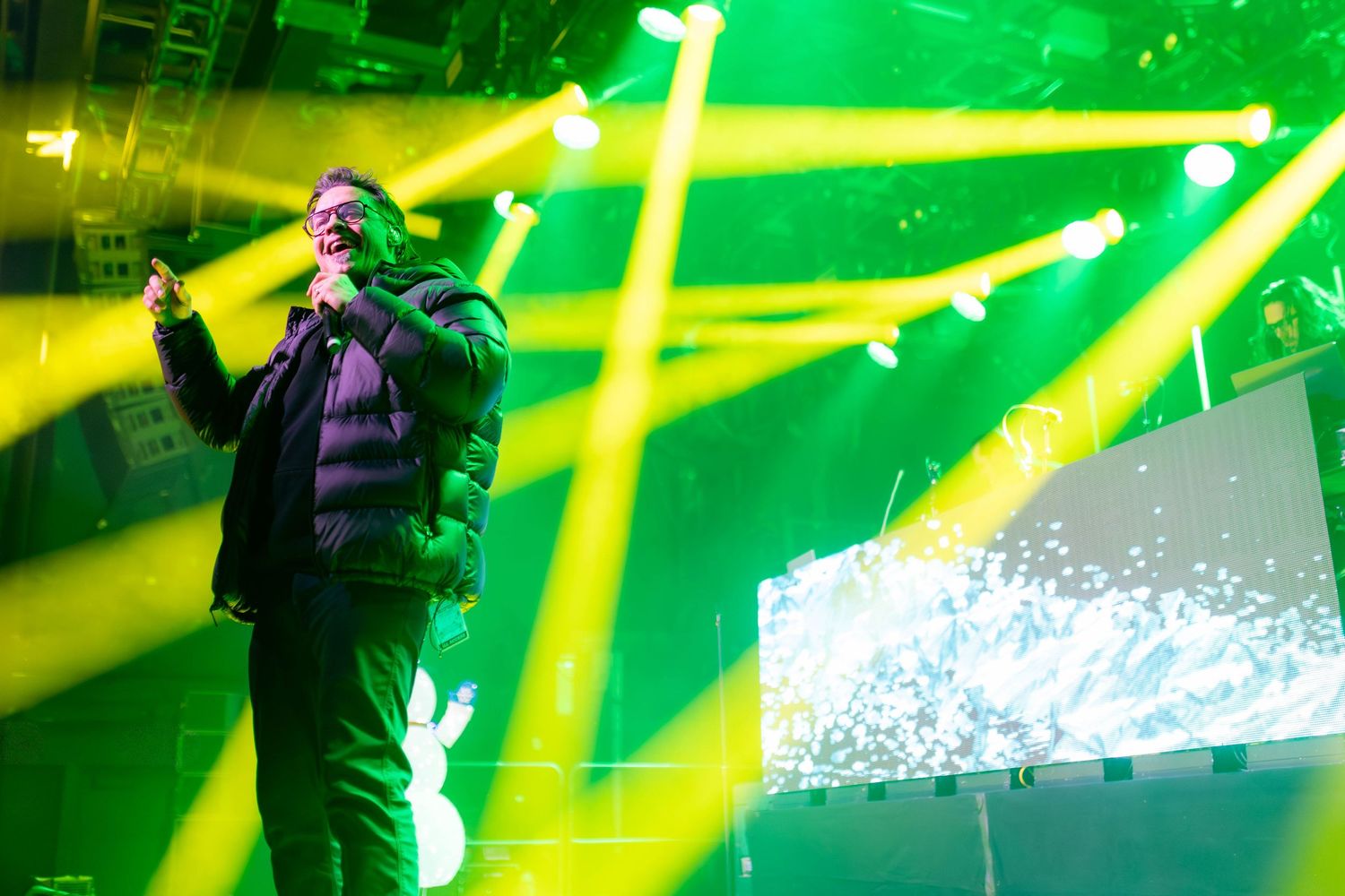Concert stage illuminated with crossing beams of green and yellow lights during performance. Brooklyn Steel