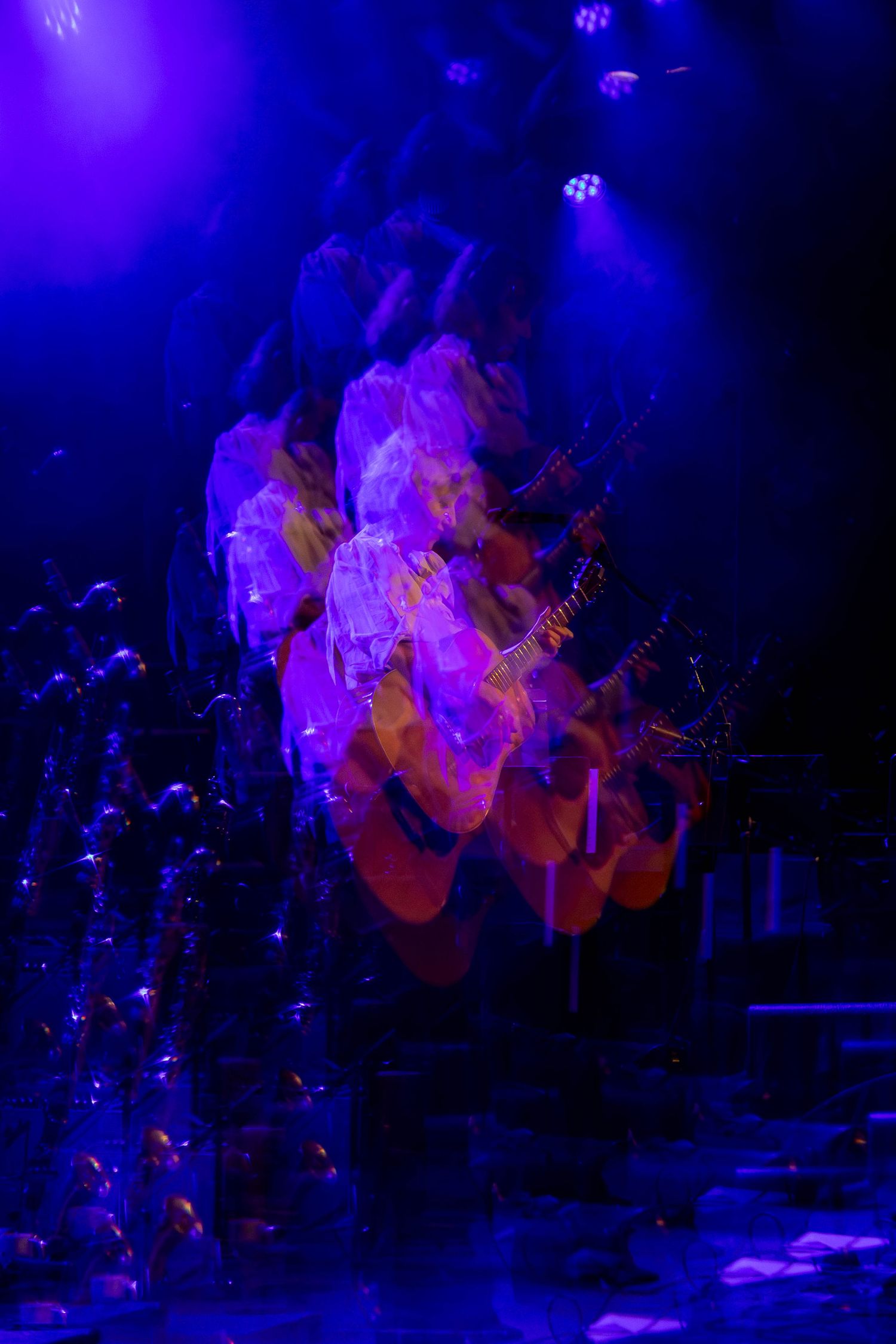 Concert stage bathed in deep blue and purple lighting creates ethereal atmosphere during performance.
