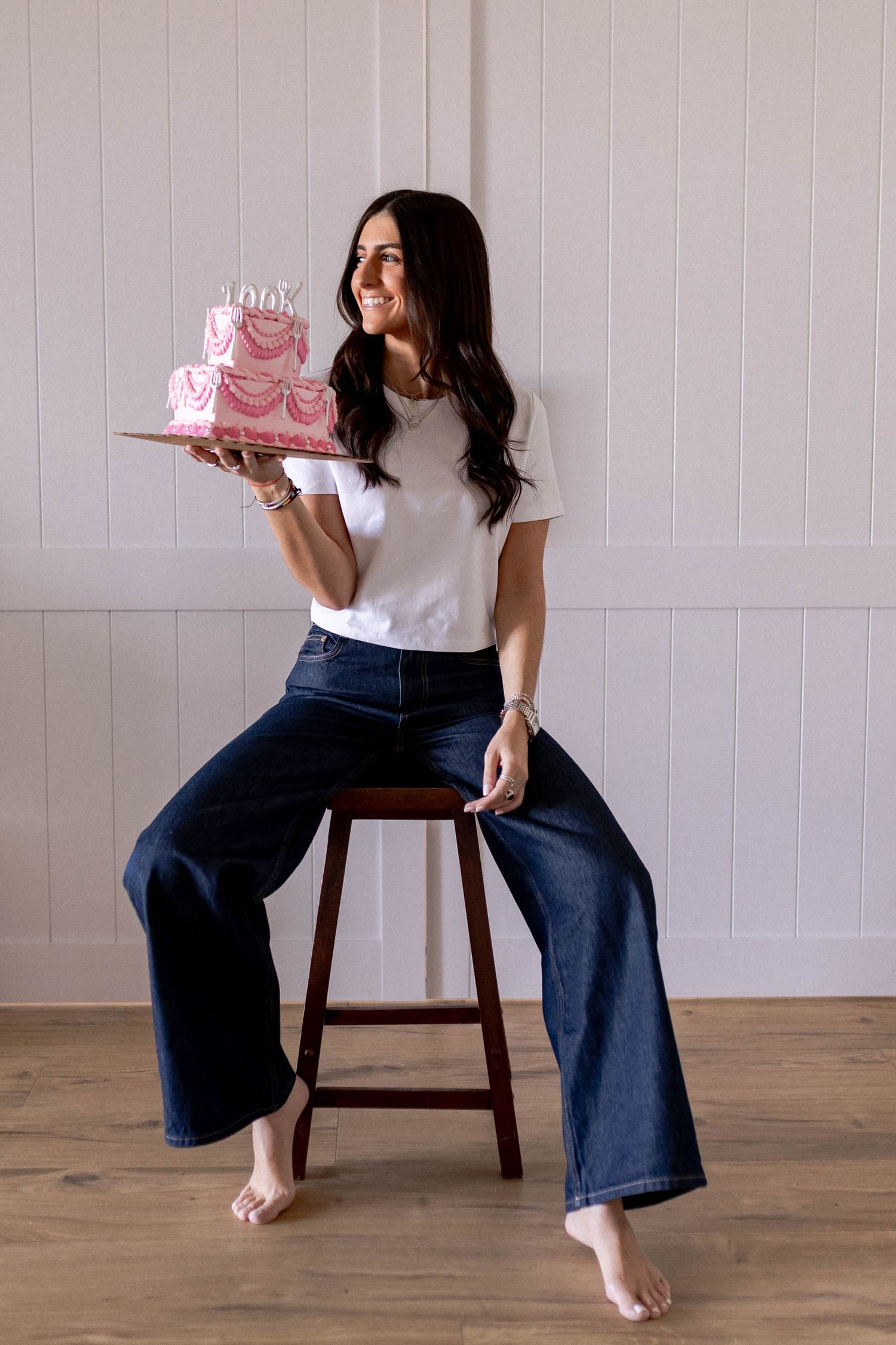 Series showing playful interactions with pink tiered cake in bright studio setting.