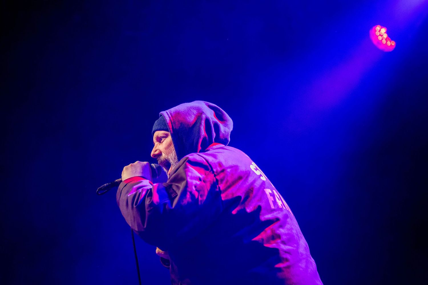 Concert performance captured in deep blue stage lighting creating moody atmosphere. Brooklyn Steel
