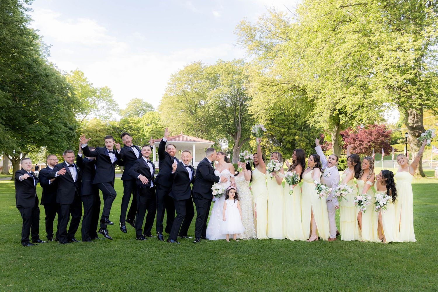 Wedding party members lined up in formal attire on a grassy lawn during an outdoor celebration.