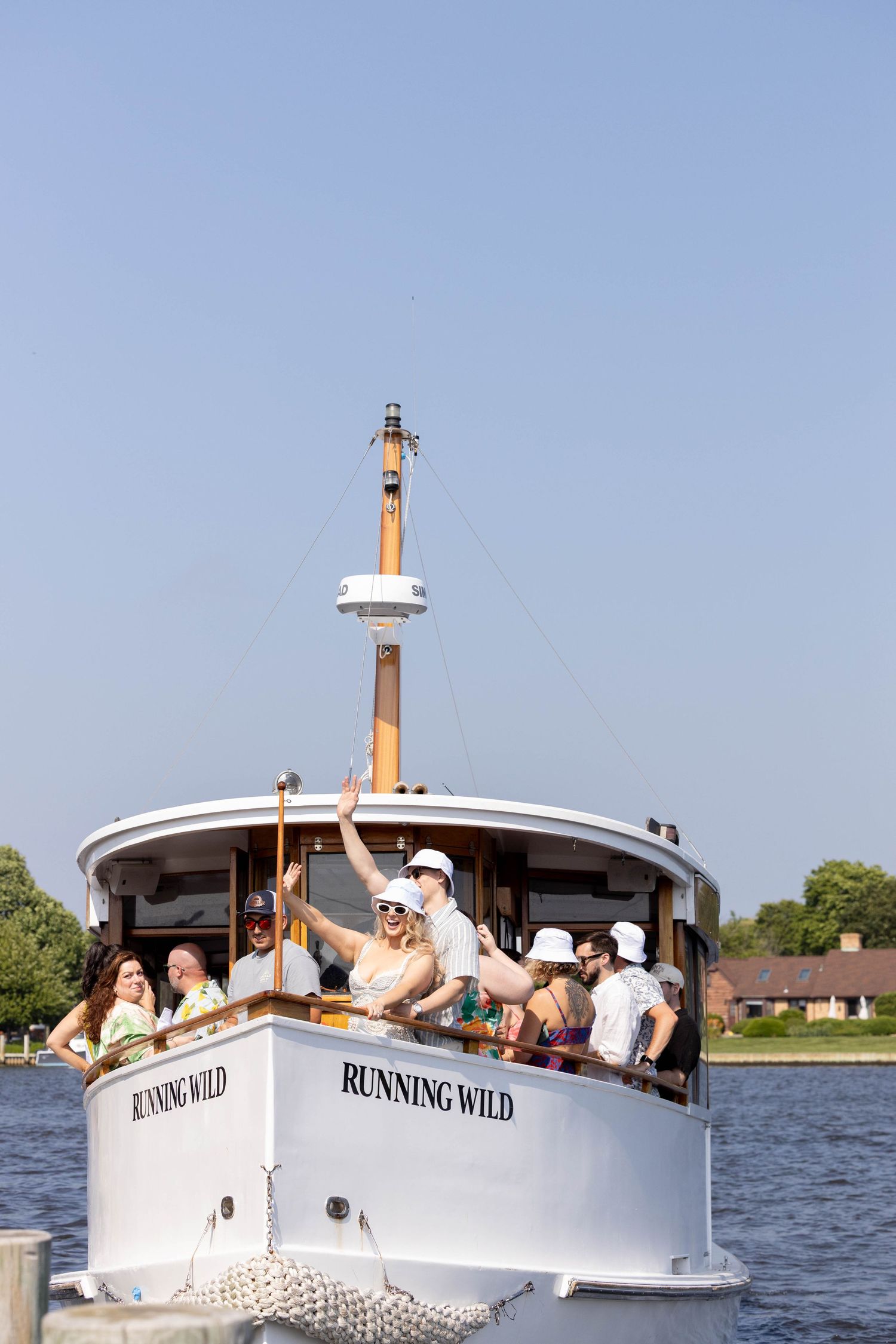 The boat 'Running Wild' filled with passengers cruising along a waterfront with homes visible.