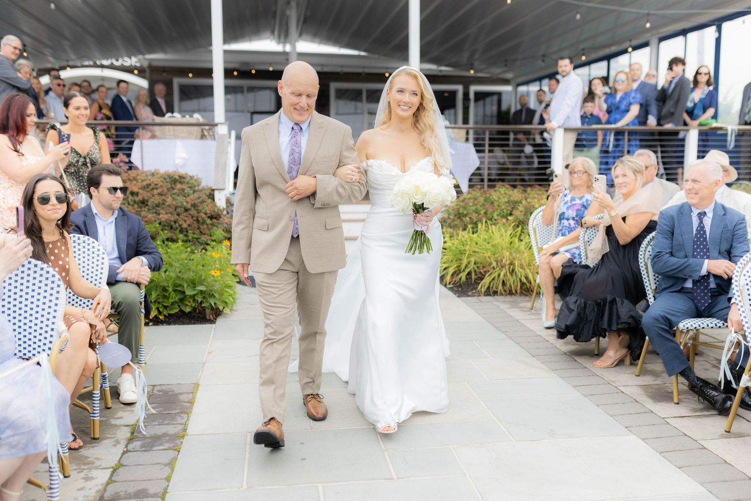 Guests seated outdoors at a wedding ceremony with a scenic garden backdrop.