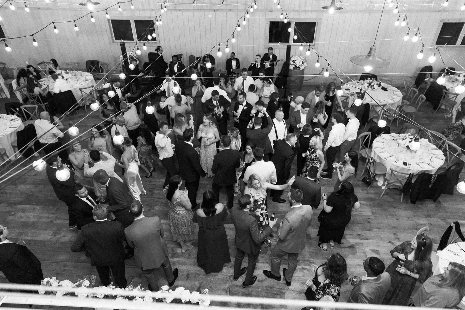 A large group of people gathered under string lights at an outdoor evening event.