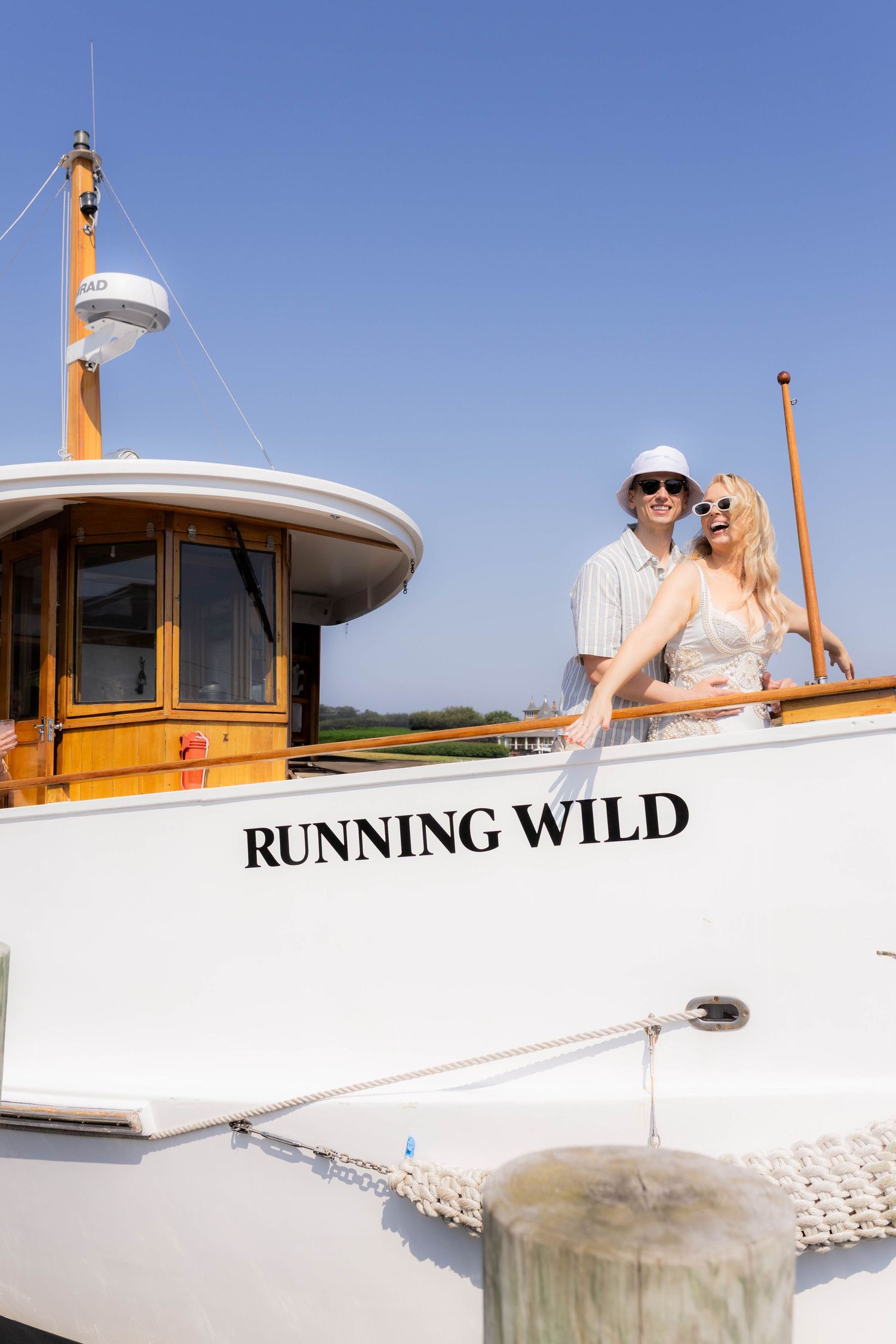 White yacht named Running Wild cruising on calm waters under blue sky on a sunny day.