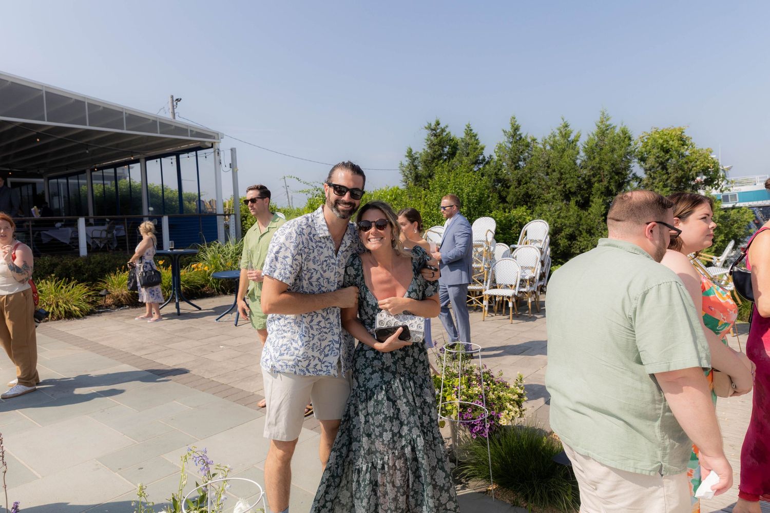 Guests mingle and socialize at an outdoor waterfront venue during a summer celebration.