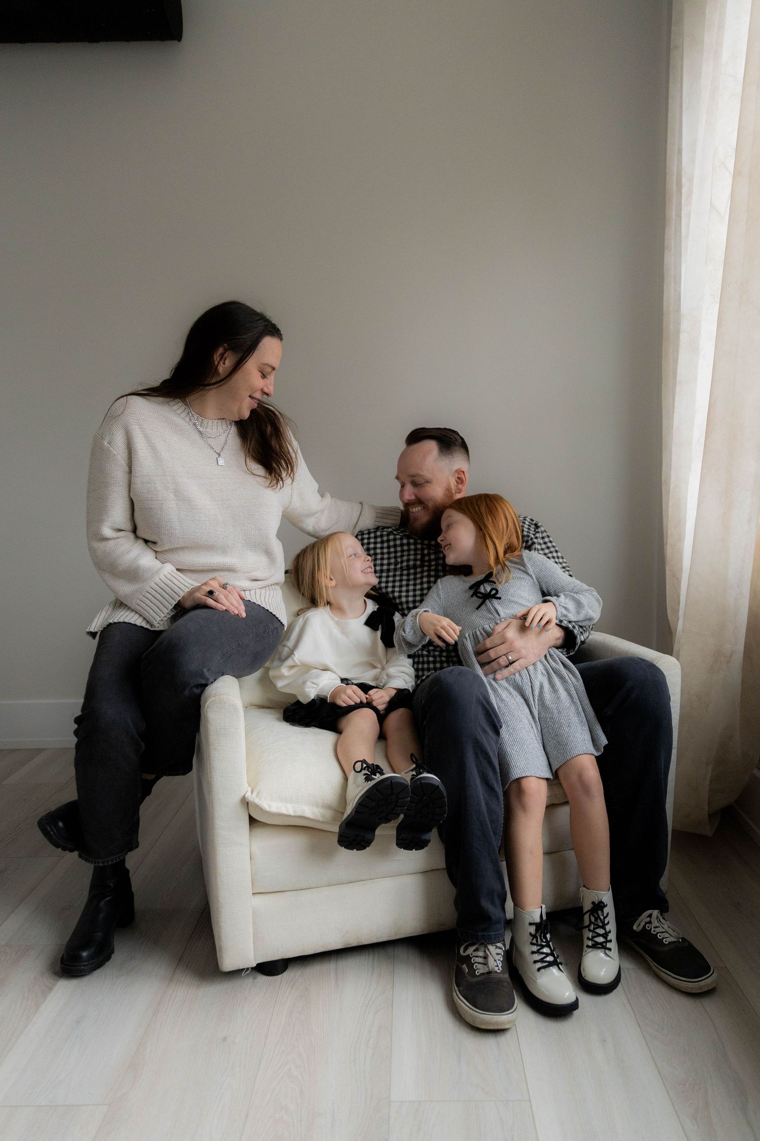 A family shares intimate moments together on a white couch indoors. Huntington Loft. Fireside Sparrow Photography