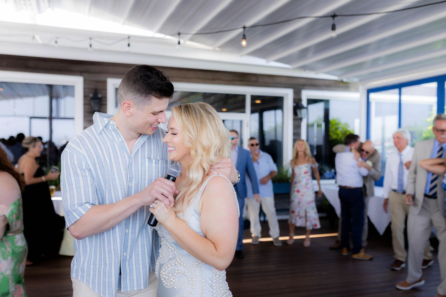 Couples dancing together in a bright white room during a social gathering or celebration event.