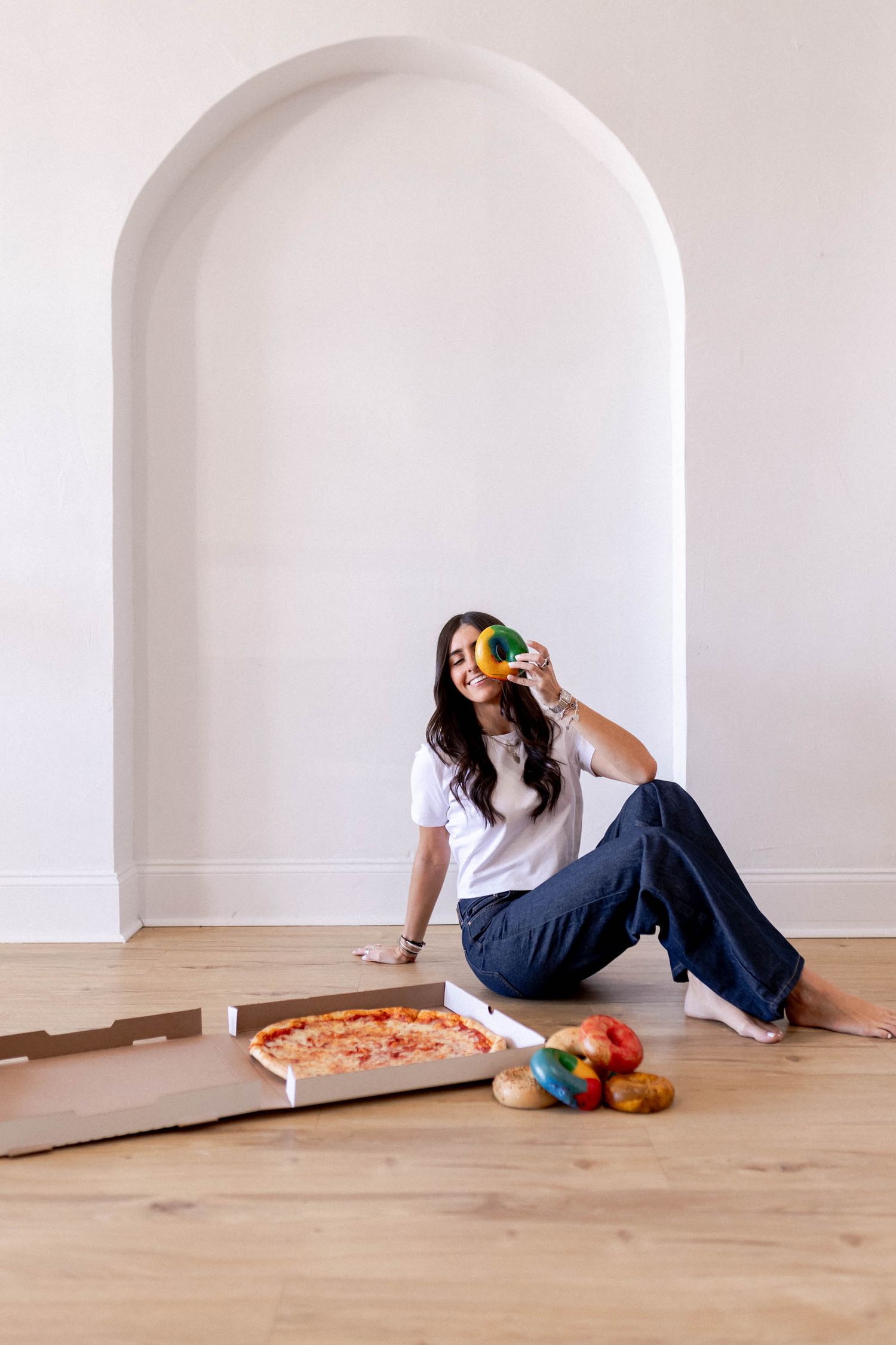 Creative photo sequence of person sitting with pizza and produce against white arched wall.