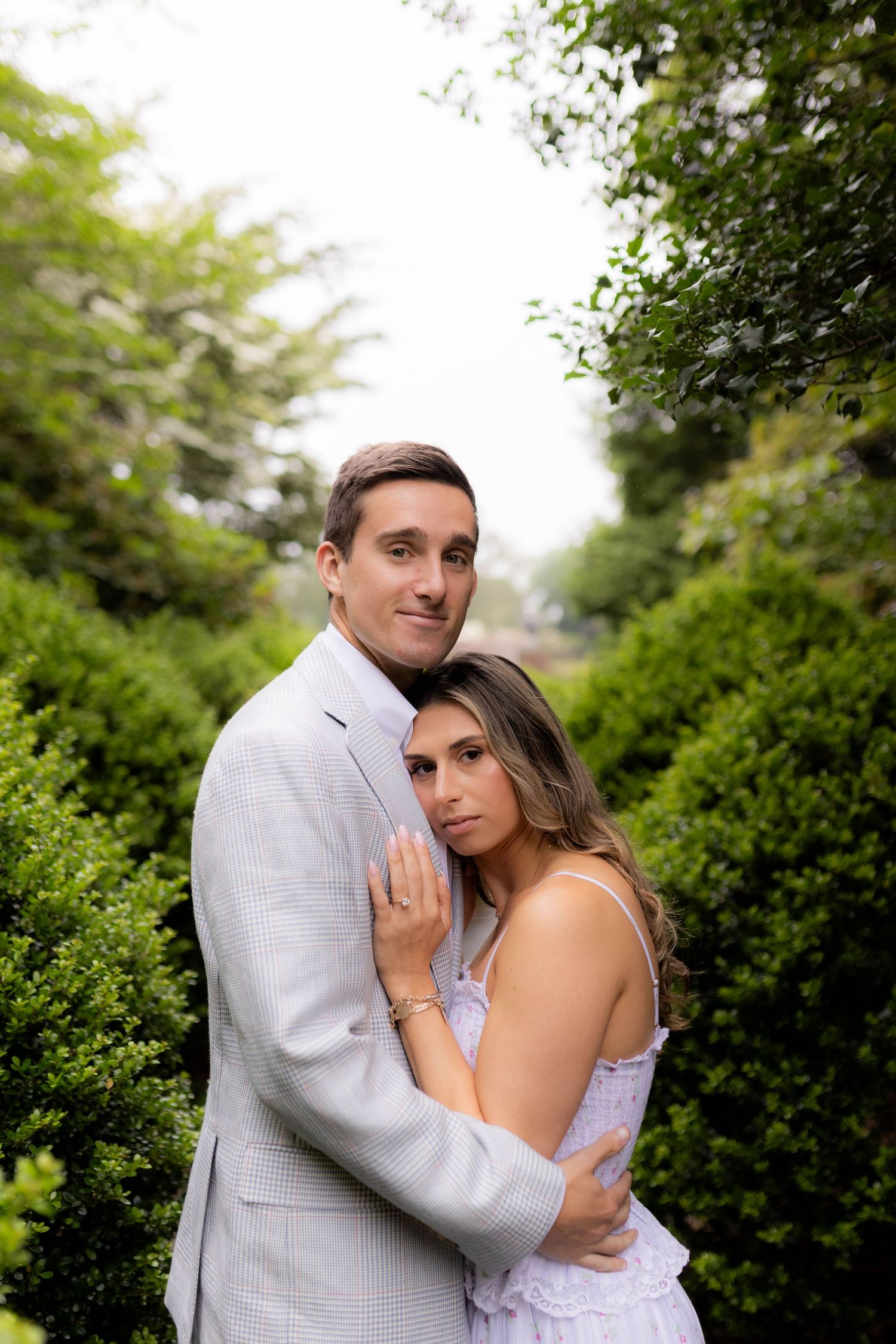 Romantic couple embracing outdoors against a backdrop of lush green foliage.