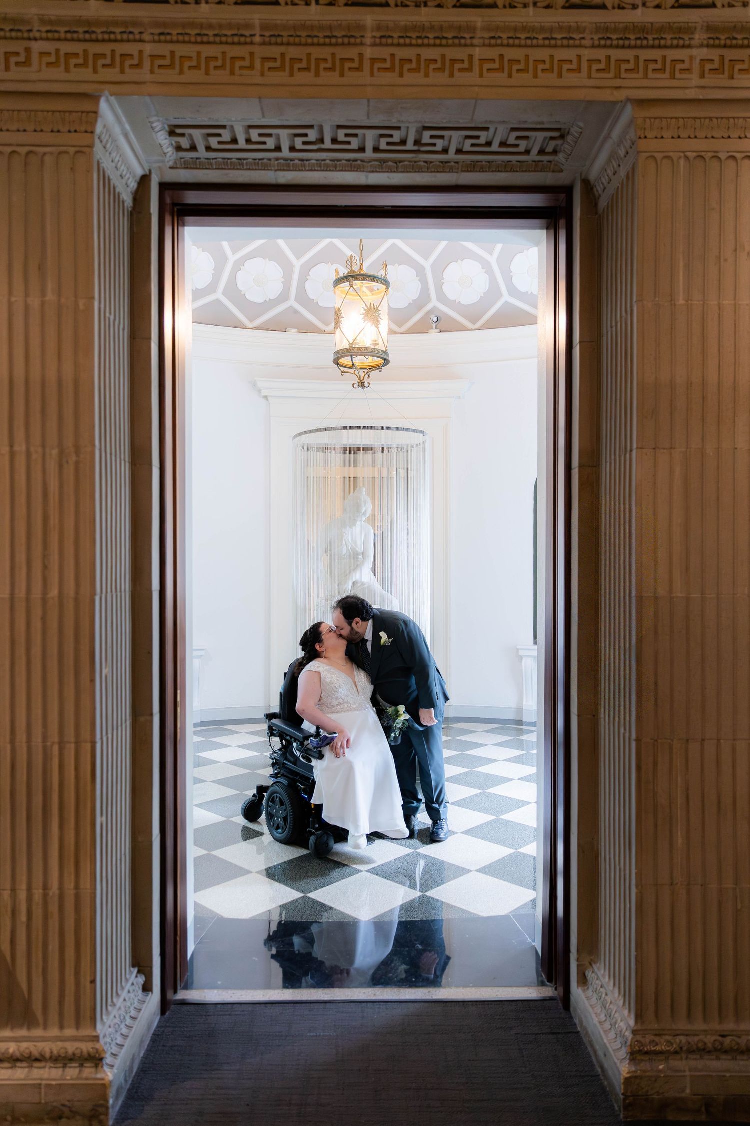 A romantic moment captured through an ornate doorway with a checkered floor.