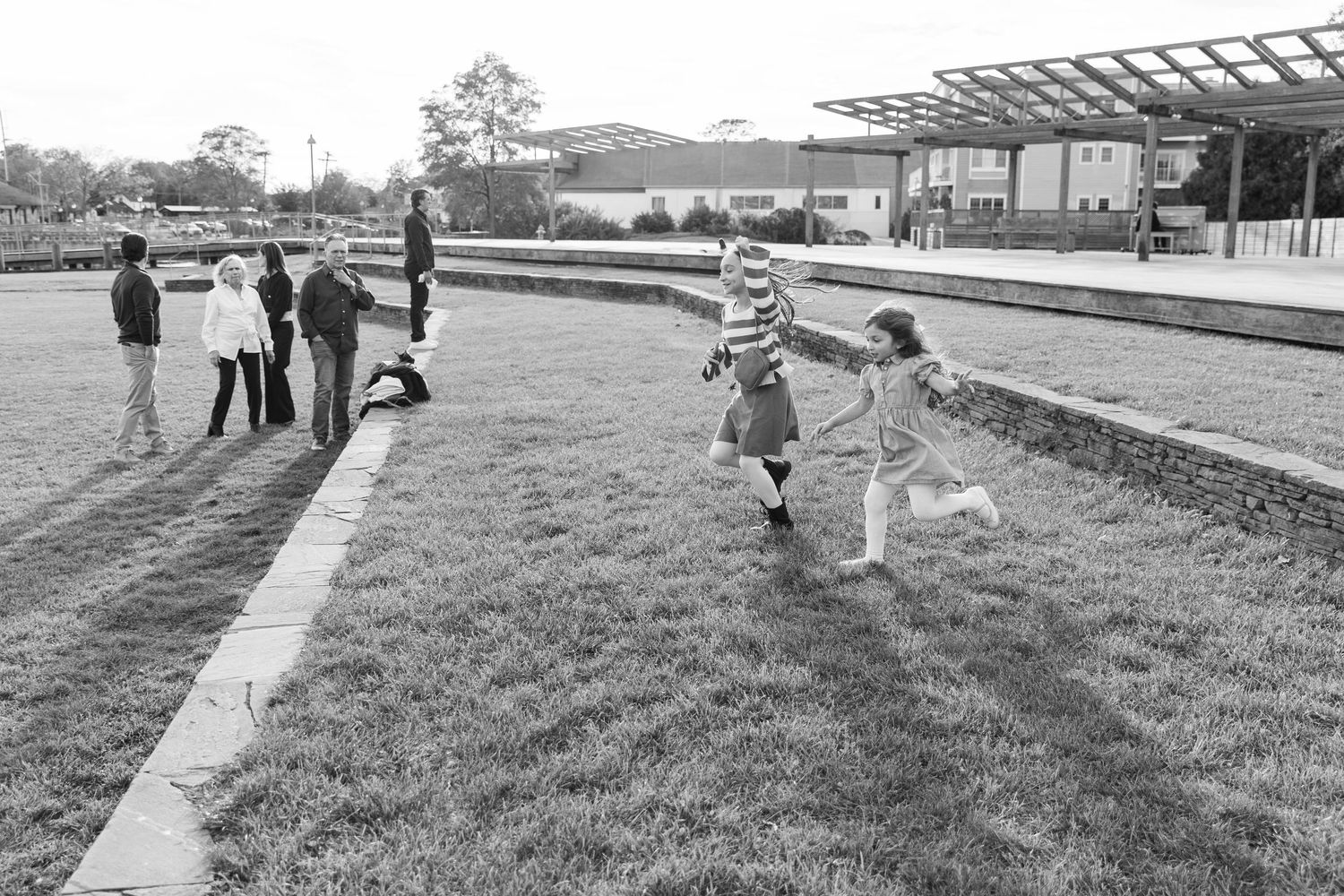 Black and white candid photo of people gathered outdoors near pathway.