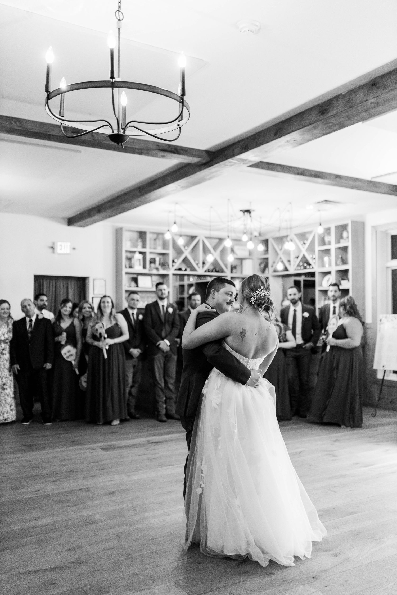 A couple shares their first dance at a wedding reception while guests watch from the sidelines.