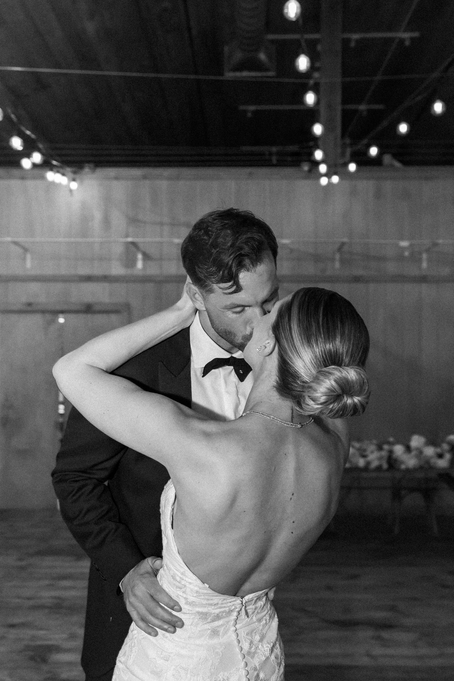 A romantic black and white wedding photo series showing a couple dancing intimately in a dimly lit venue.
