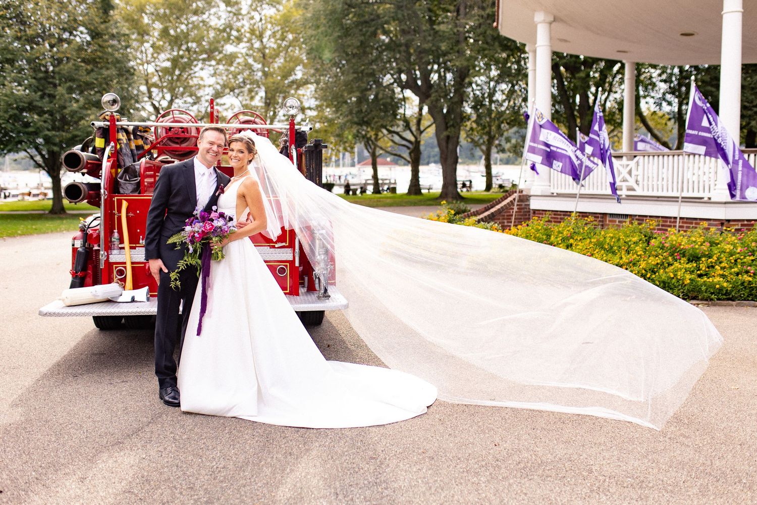 Wedding couple poses for romantic portraits in a lush garden setting with a white gown flowing in the breeze.