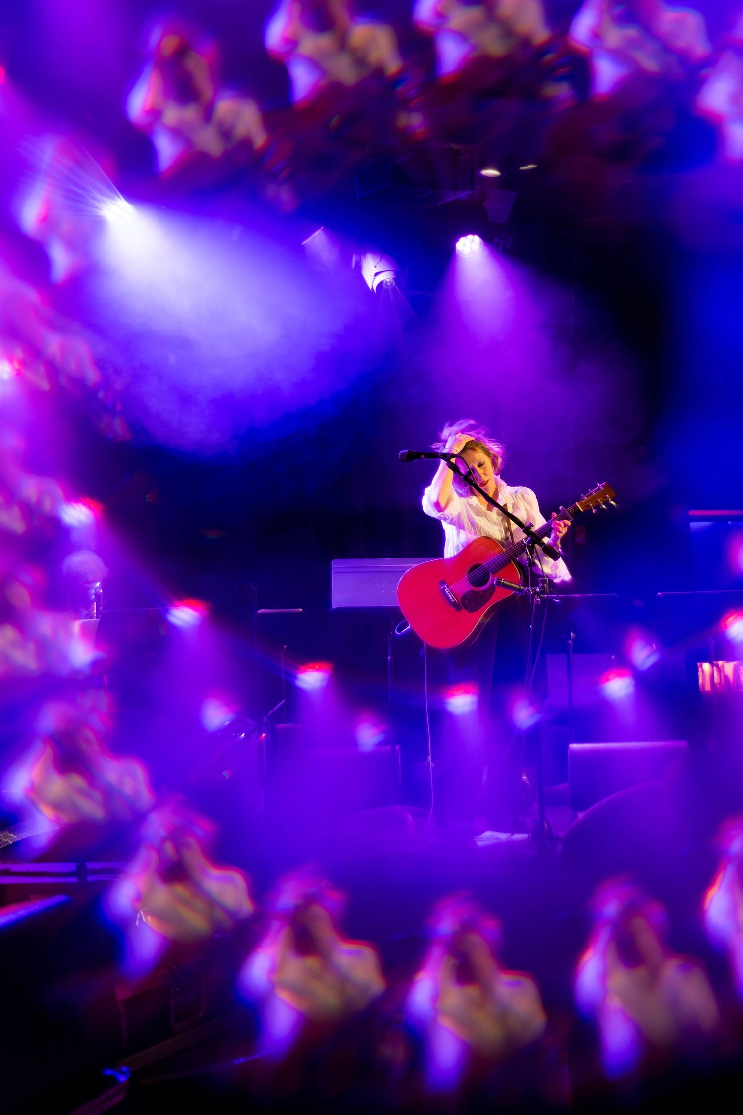 Artistic concert photography with purple haze and bokeh effects framing performer on stage.