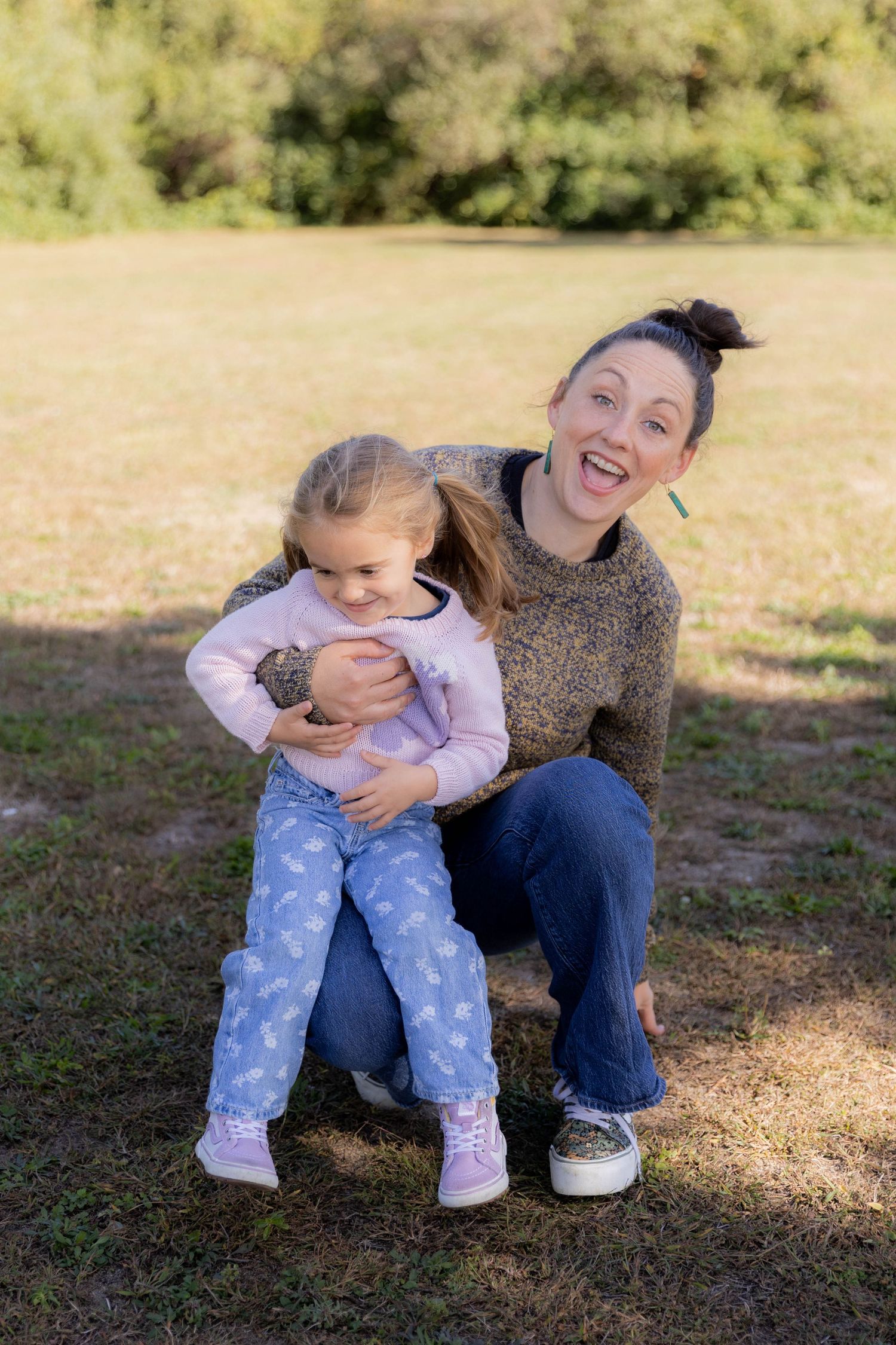 Two people share a playful moment while sitting on grass outdoors. Fireside Sparrow Photography