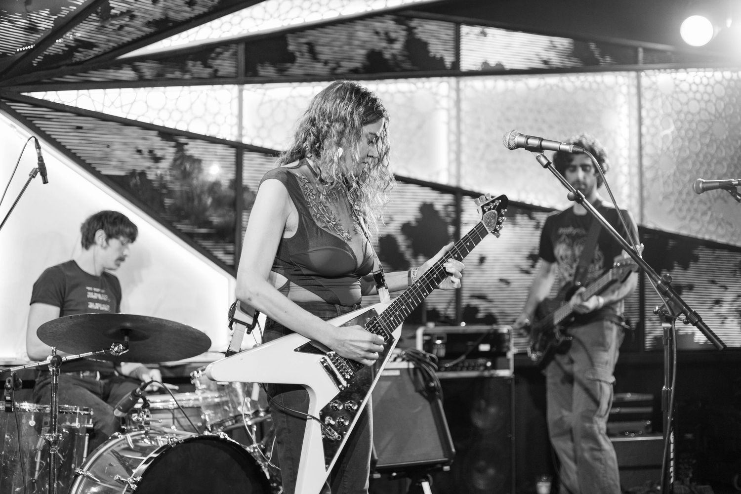 Musicians perform on stage with dramatic black and white lighting effects creating a moody atmosphere.