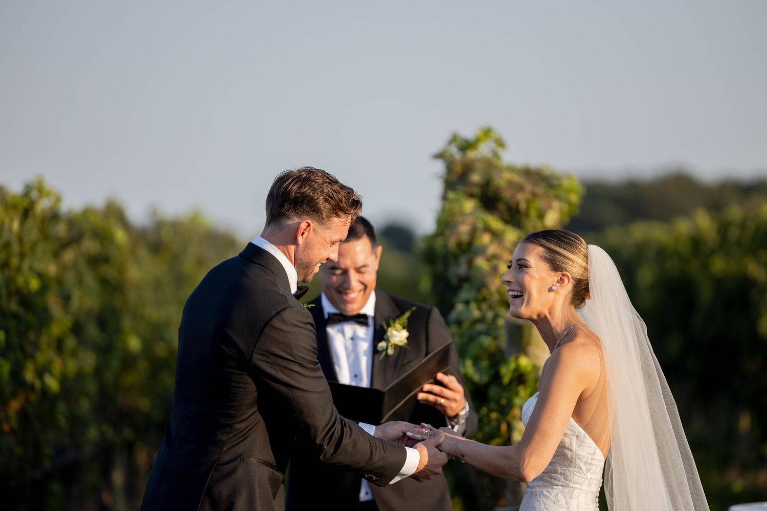 A romantic moment between newlyweds in a sunlit vineyard with rolling hills in the background.