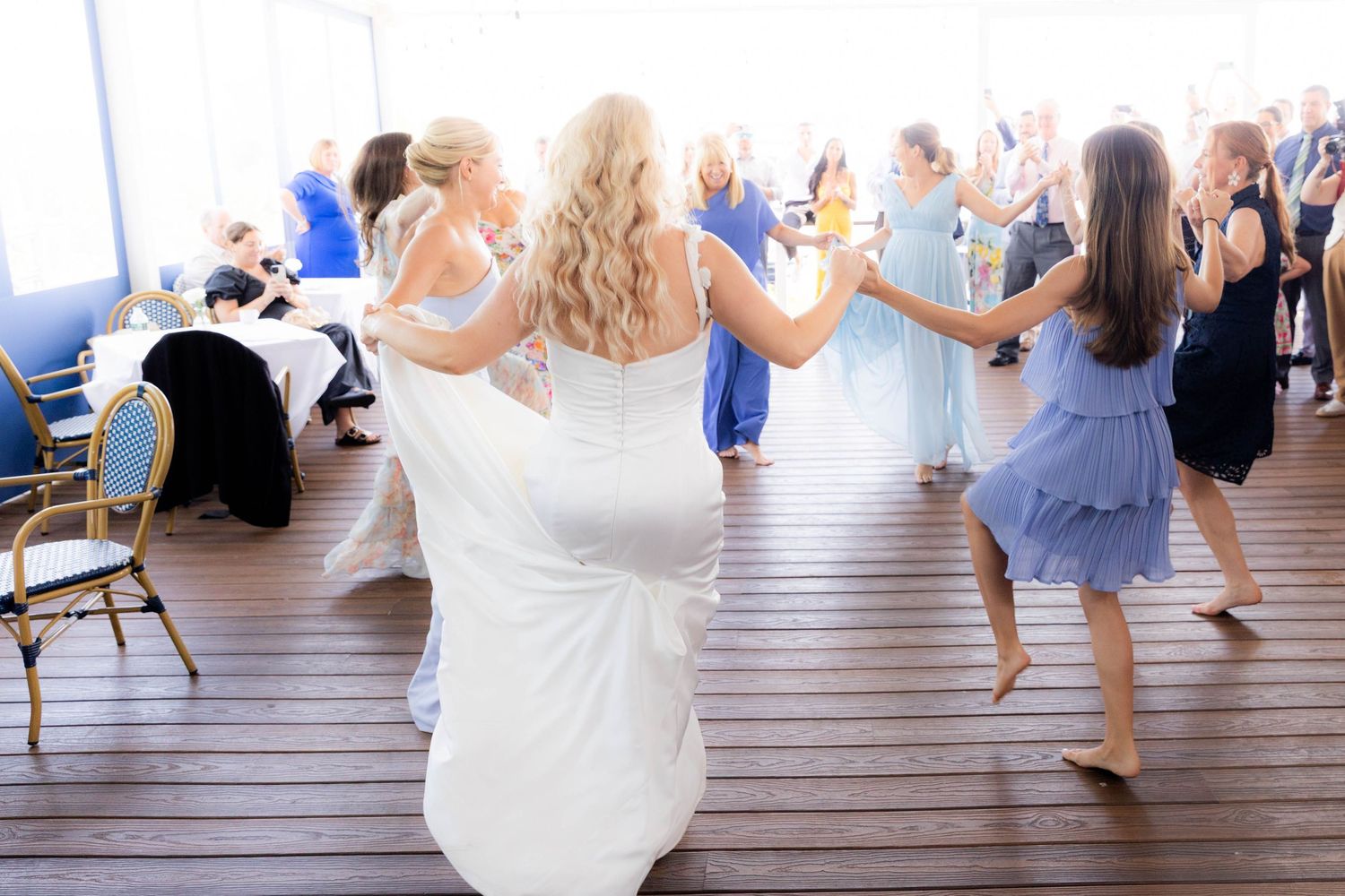 Ballet dancers in light blue and white dresses perform graceful movements in a bright dance studio.