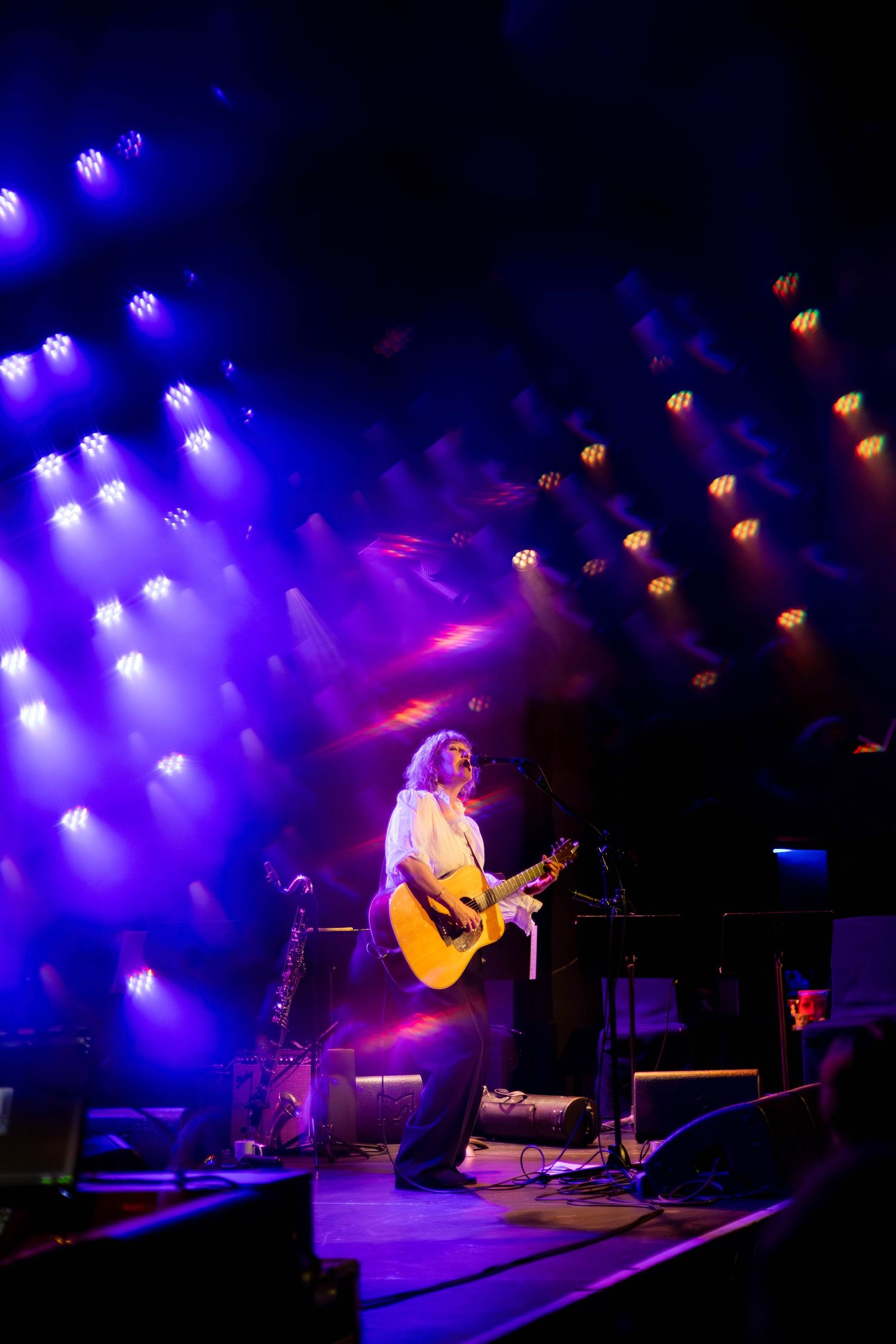 Performers on stage illuminated by dramatic purple and blue spotlights during live show.