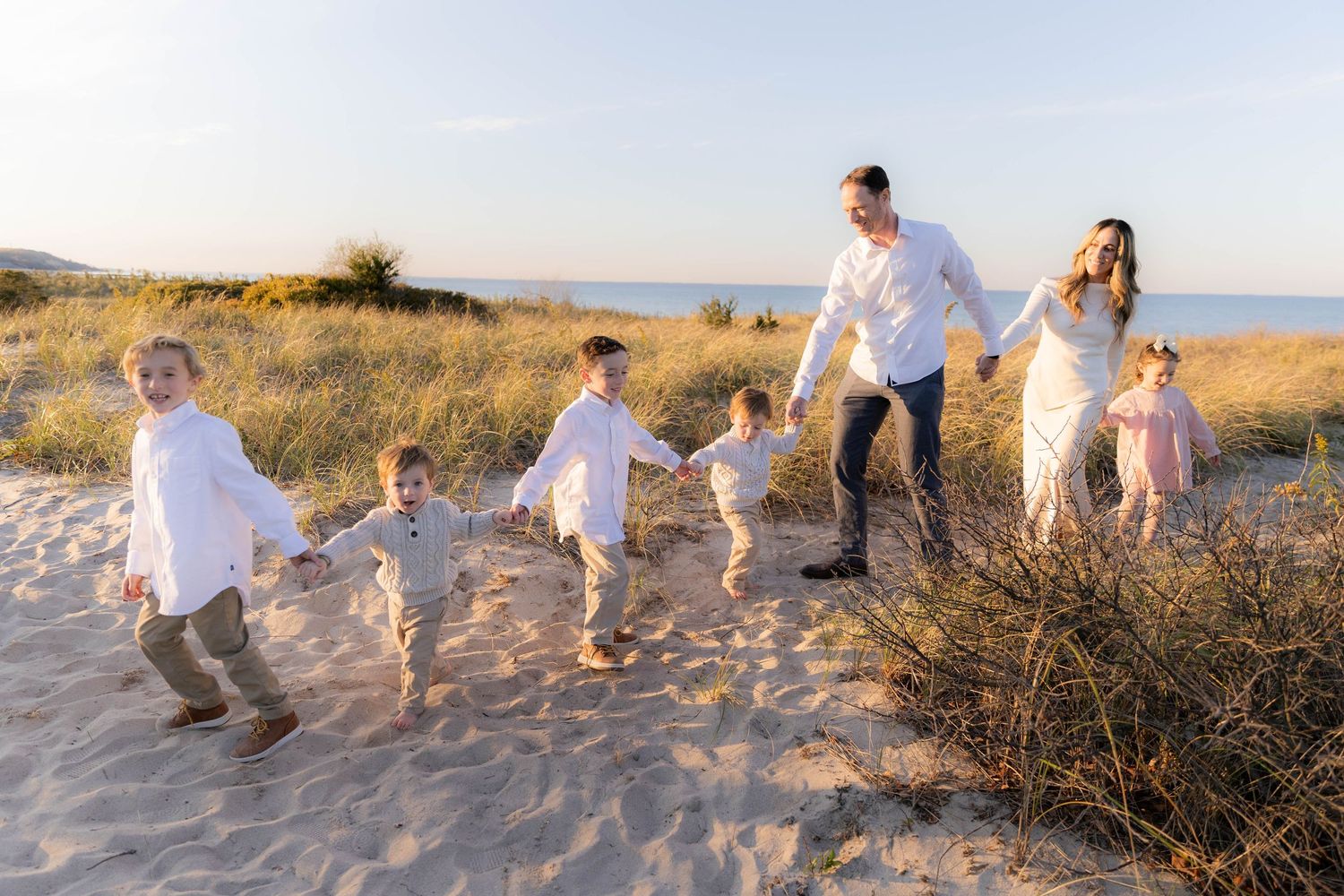 Family walking together along beach path during golden hour photoshoot.