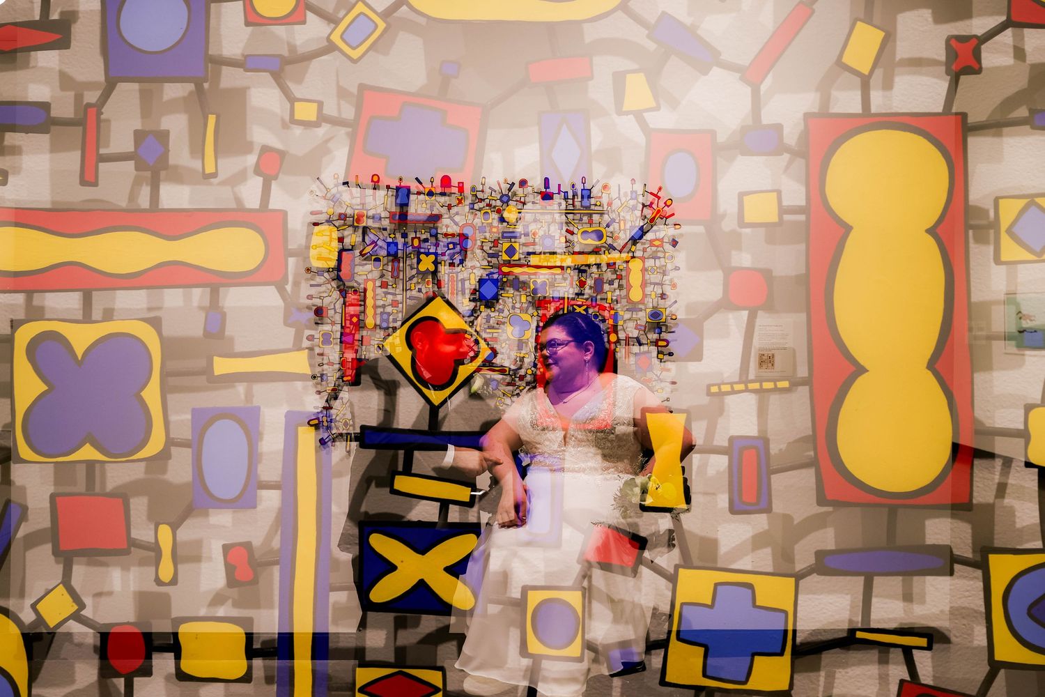 Wedding photo against a colorful geometric art wall with abstract shapes and patterns.