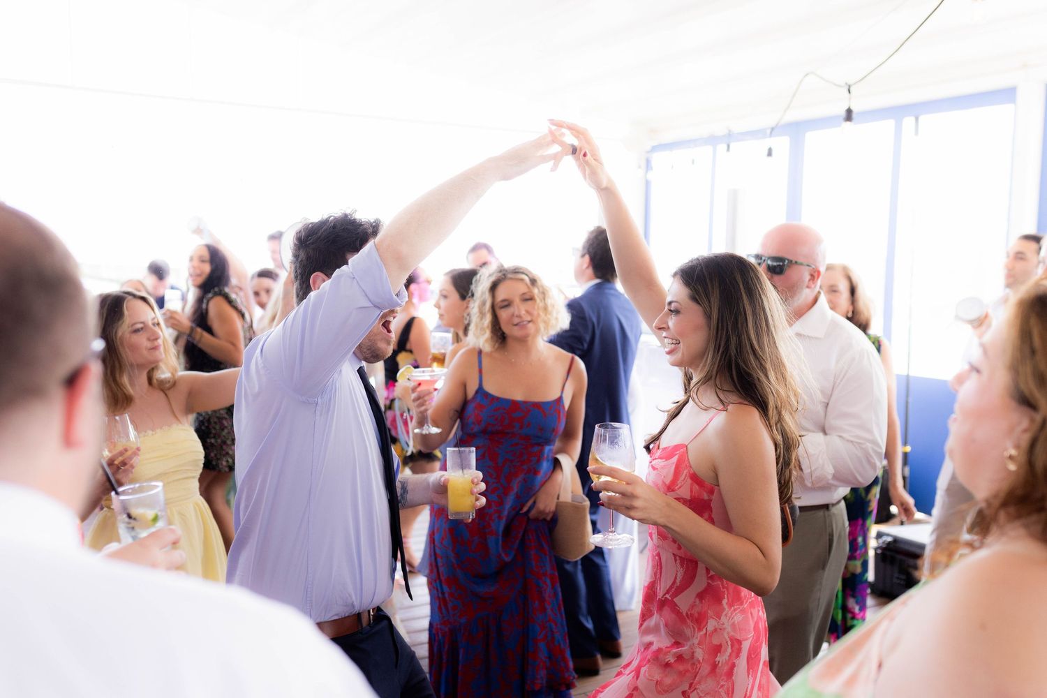 Wedding guests dance and celebrate together on a festive dance floor during a joyful reception celebration.
