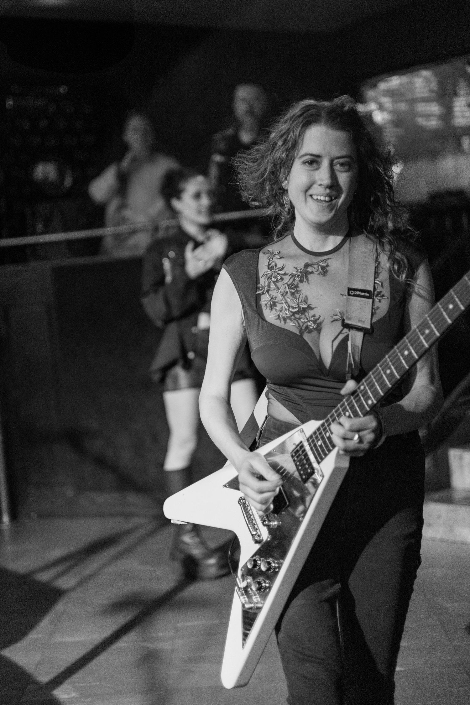 Musicians play electric guitars during a dynamic performance on a dimly lit stage.