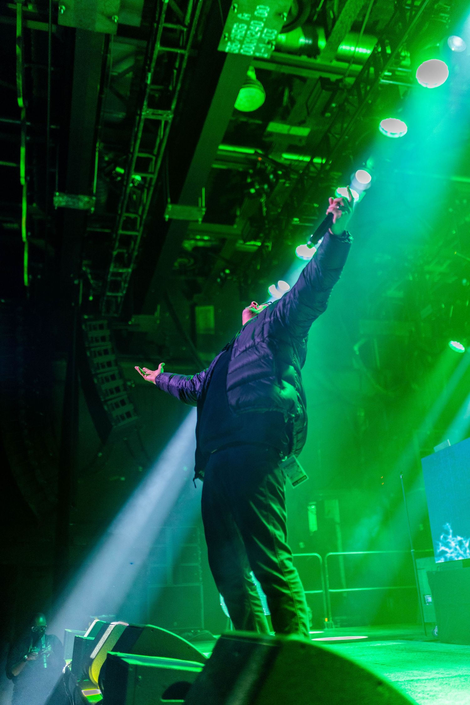 Performer silhouetted against intense green stage lighting during dynamic show.